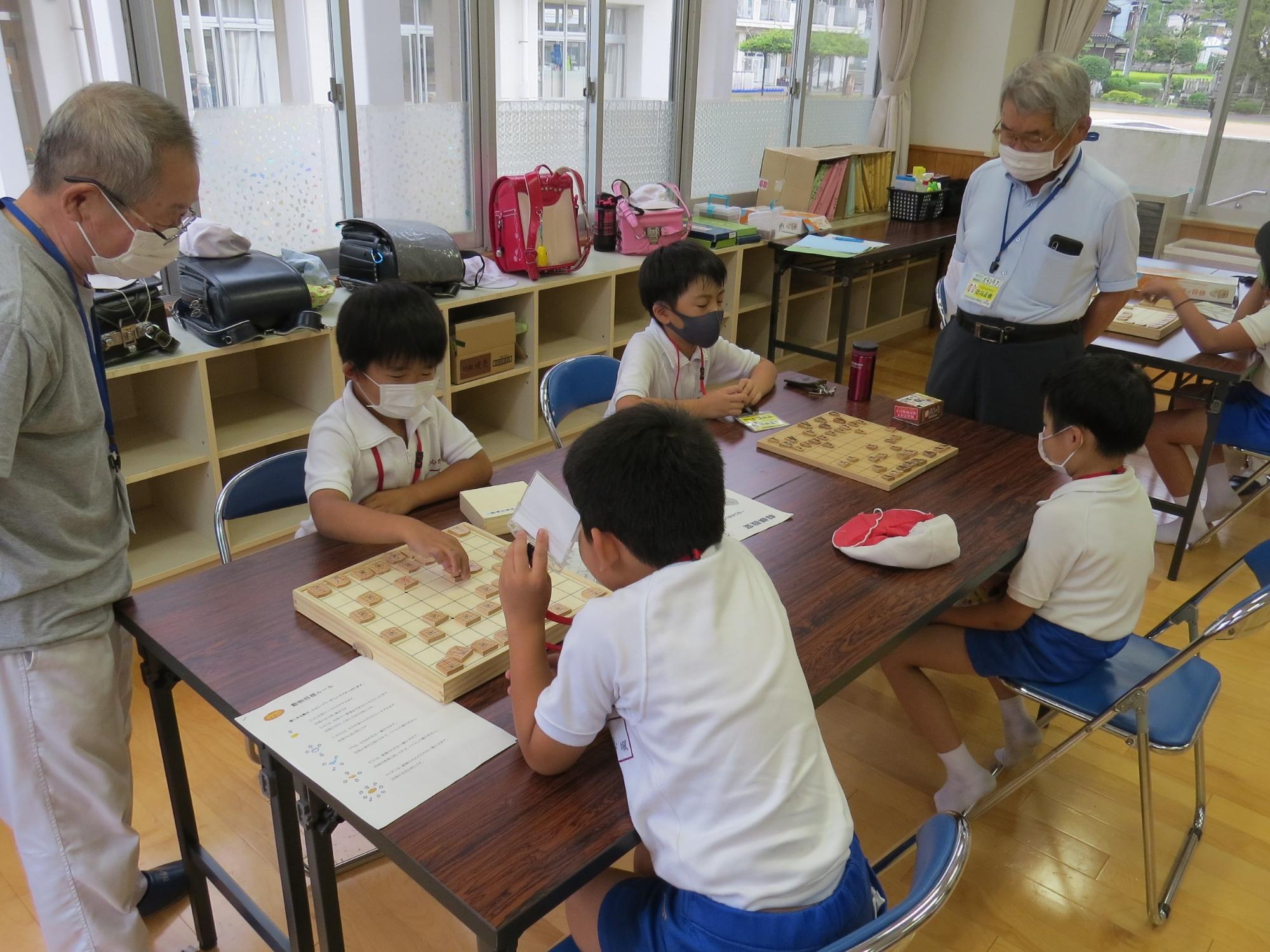 対戦相手をみつけて、将棋をしてる子どもたちと指導してくださるボランティアさんの写真