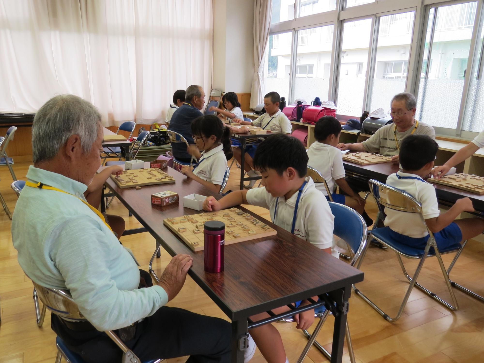 将棋教室で、ボランティアの指導員と対戦している子ども達の写真