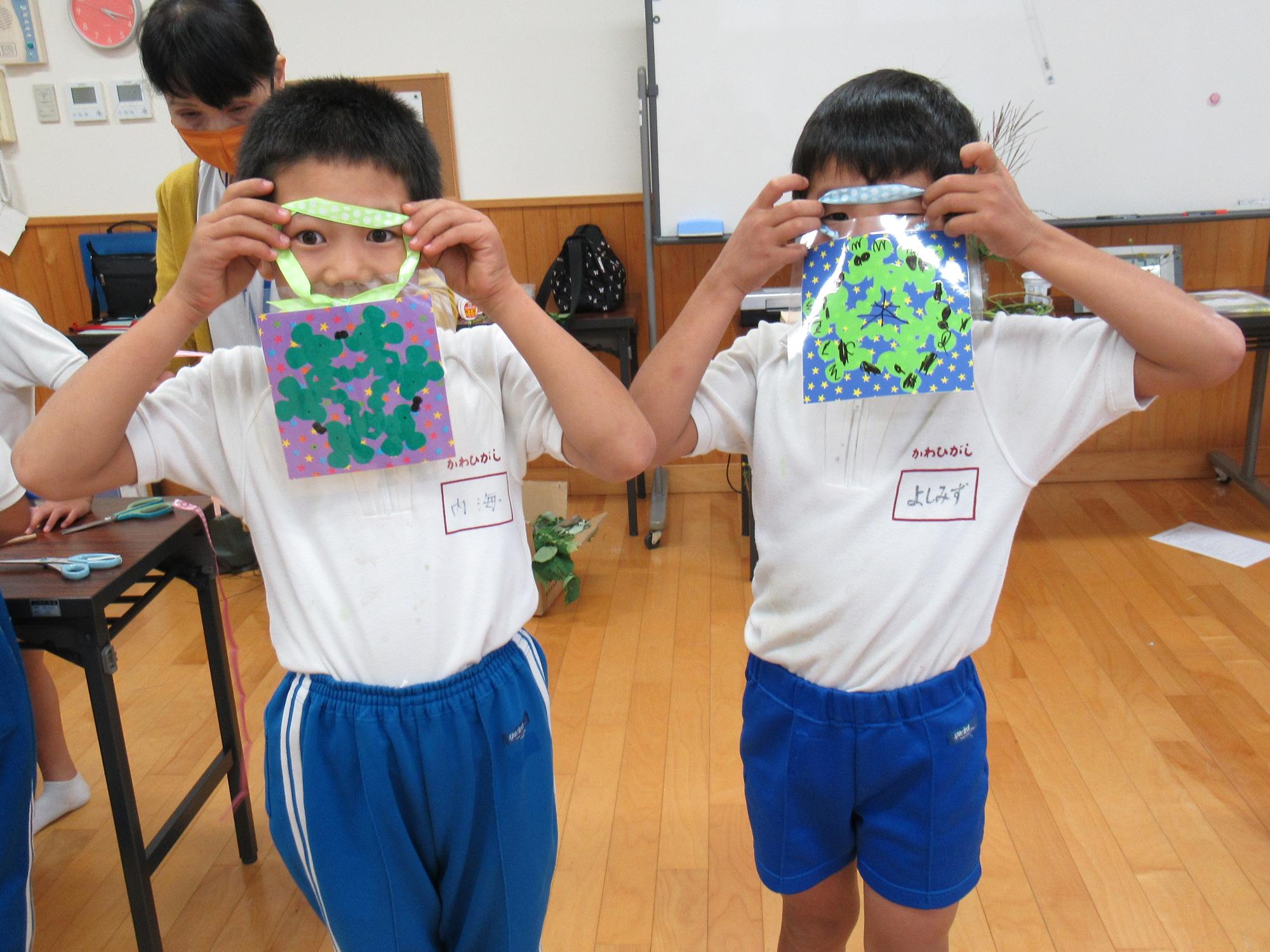 放課後子ども教室で作ったかべ飾りをうれしそうに見せてくれる二人の子どもの写真
