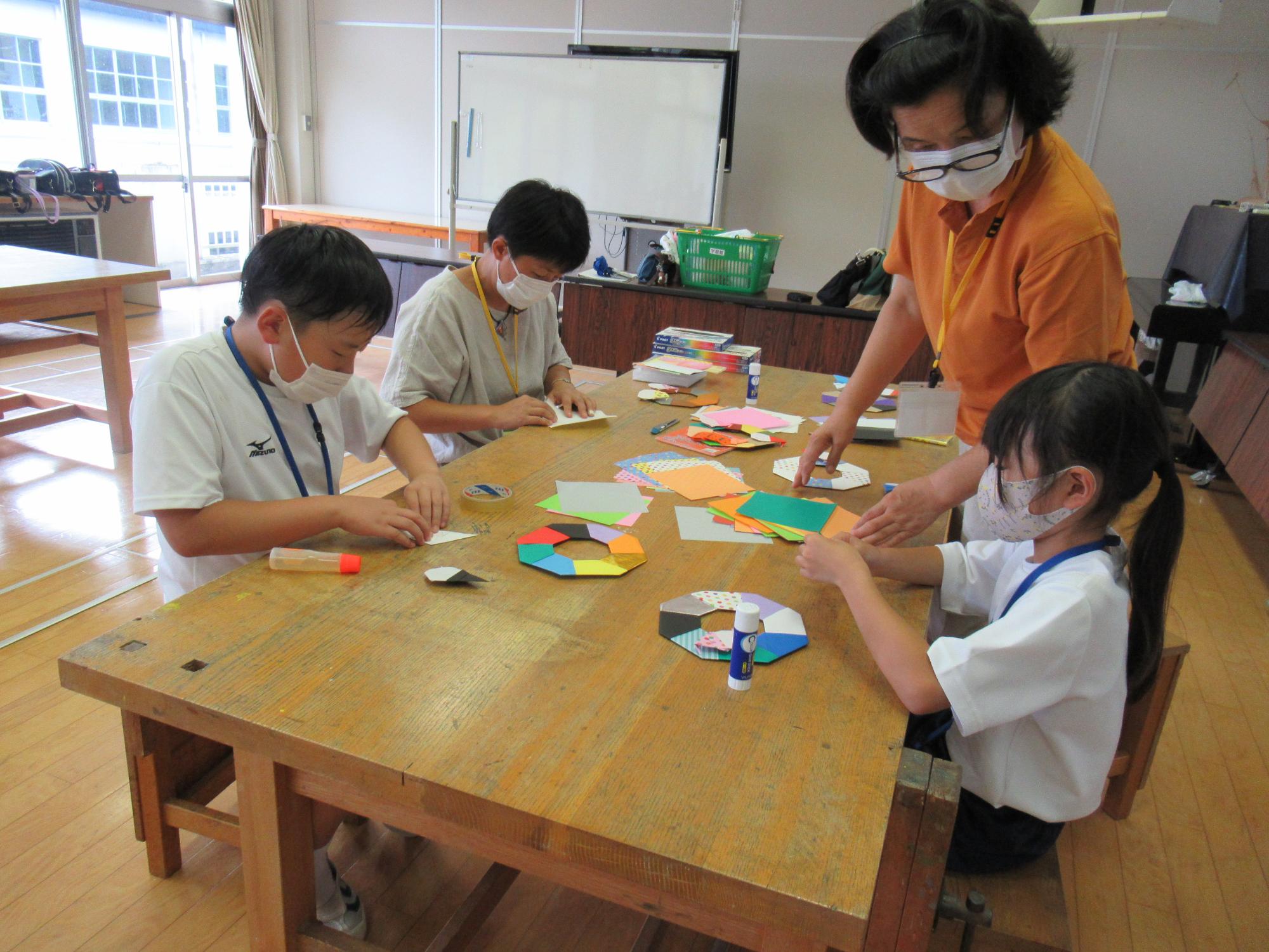 工作・仲間あそび教室で、楽しそうに折り紙工作をしている子ども達と指導者の写真