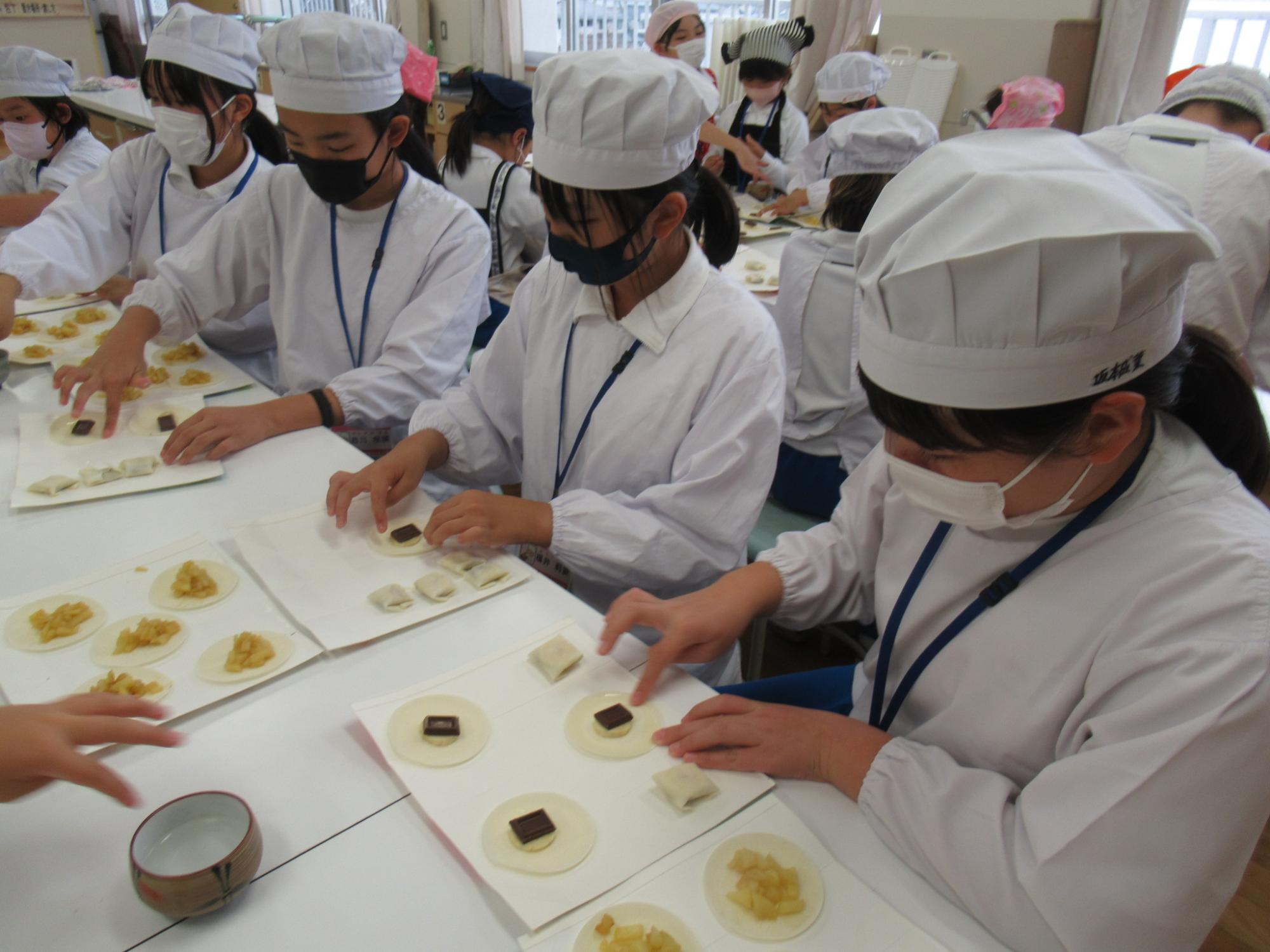 参加者が餃子の皮に具材を置いて、包んでいる写真