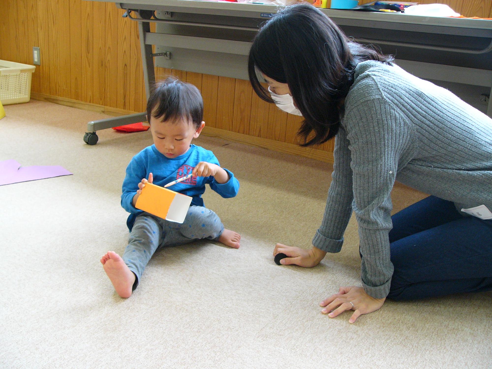 出来上がった牛乳パックおもちゃで遊ぶ男の子とお母さんの写真