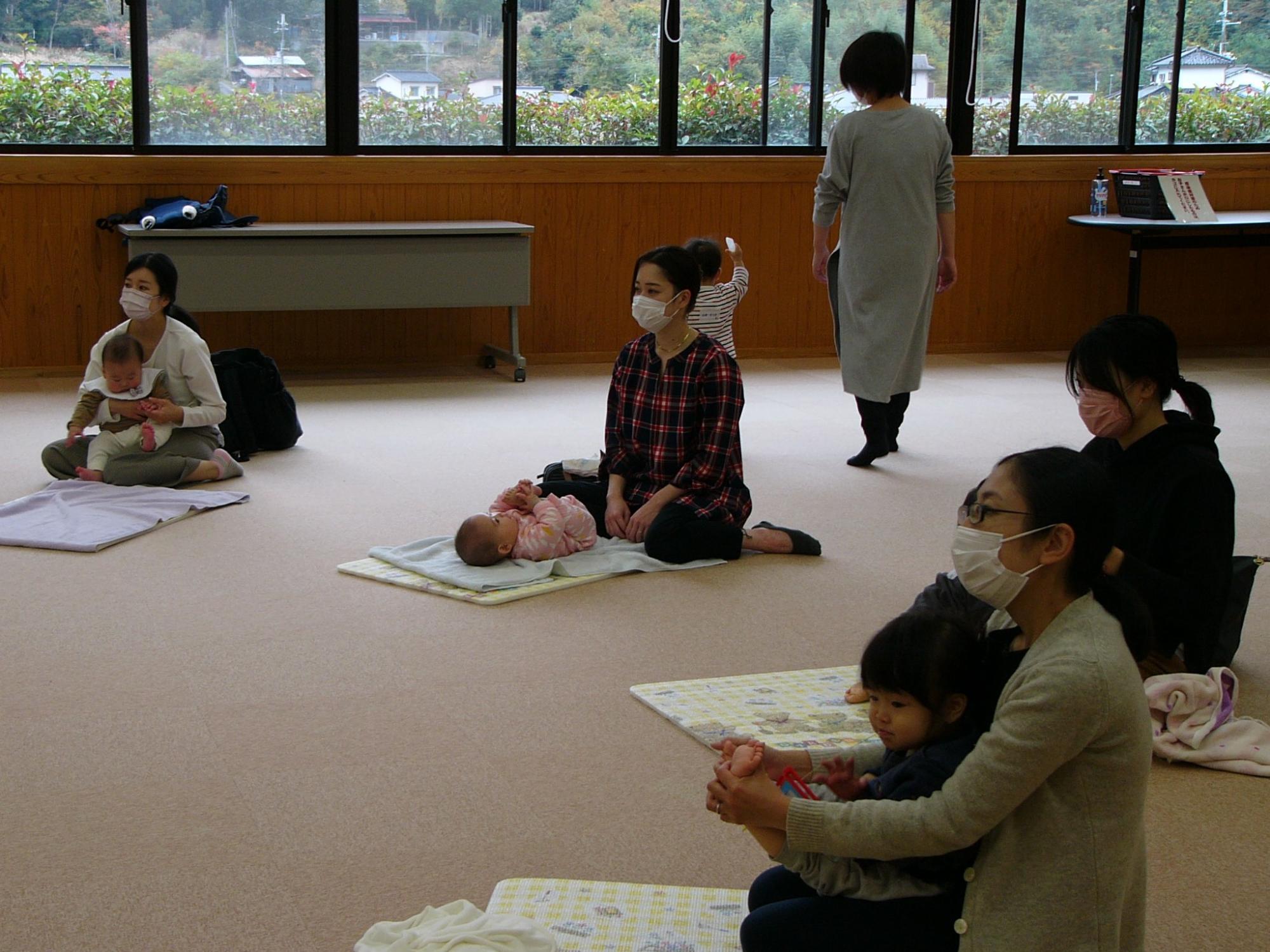 講師の先生の指導のもと、こどもとふれあってマッサージをしているお母さんたちの写真