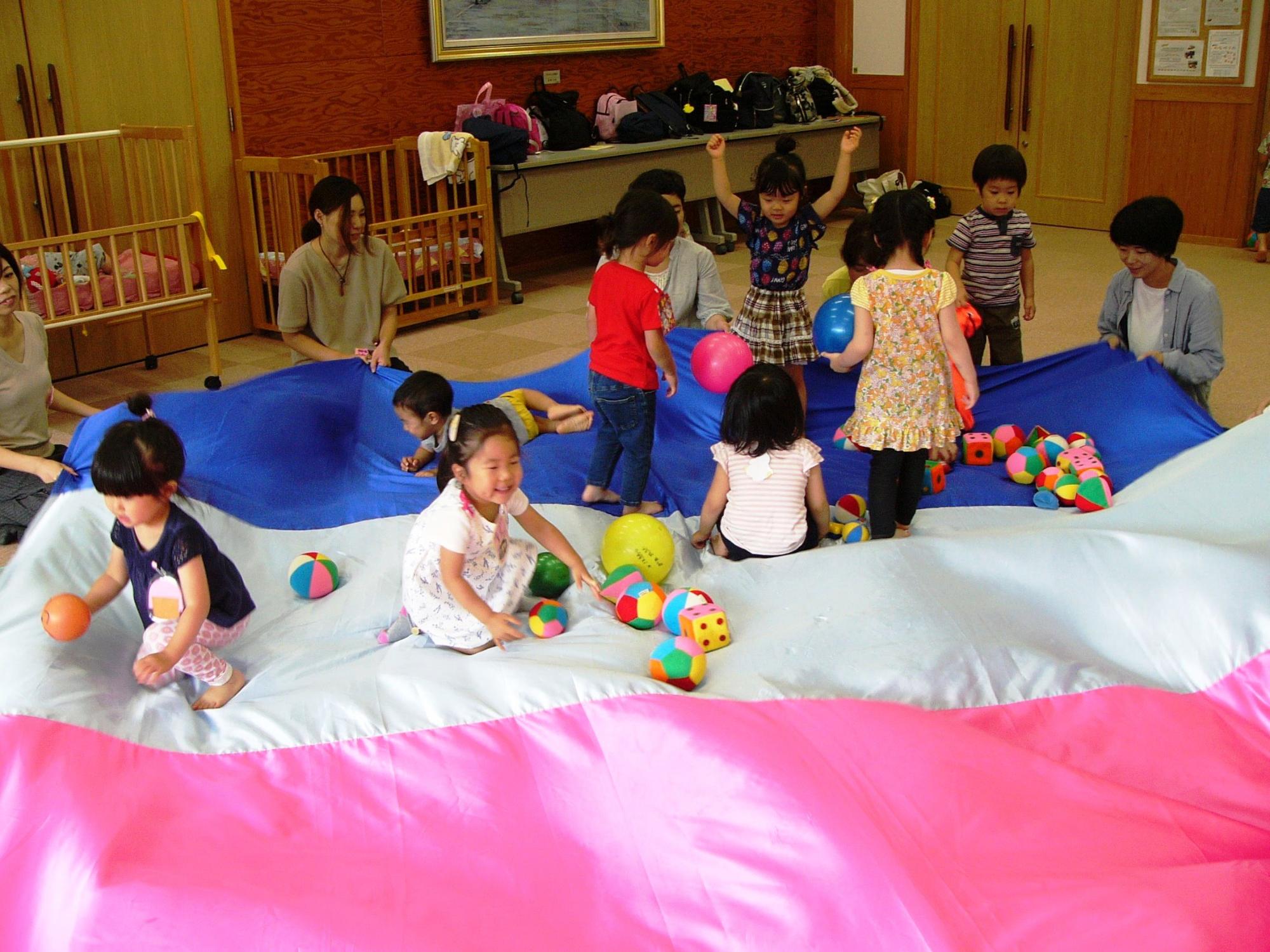 子どもたちがパラバルーンで遊んでいる写真