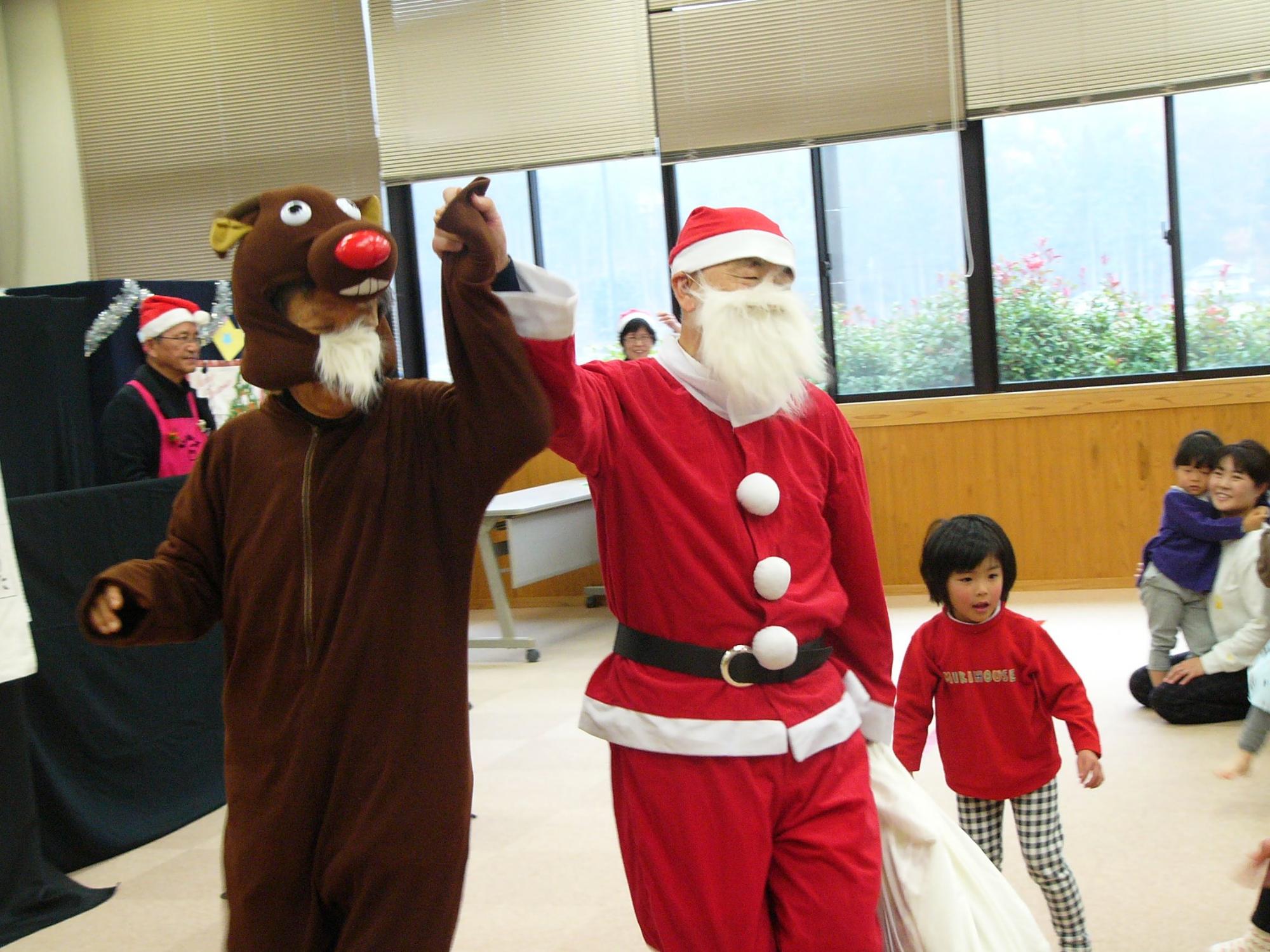 クリスマス会の会場にサンタクロースとトナカイが登場してきた写真