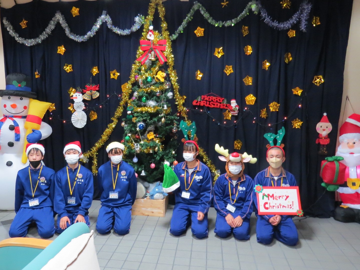 学遊館ロビーのクリスマス展示の前でトライやるの生徒らが並んで笑っている写真