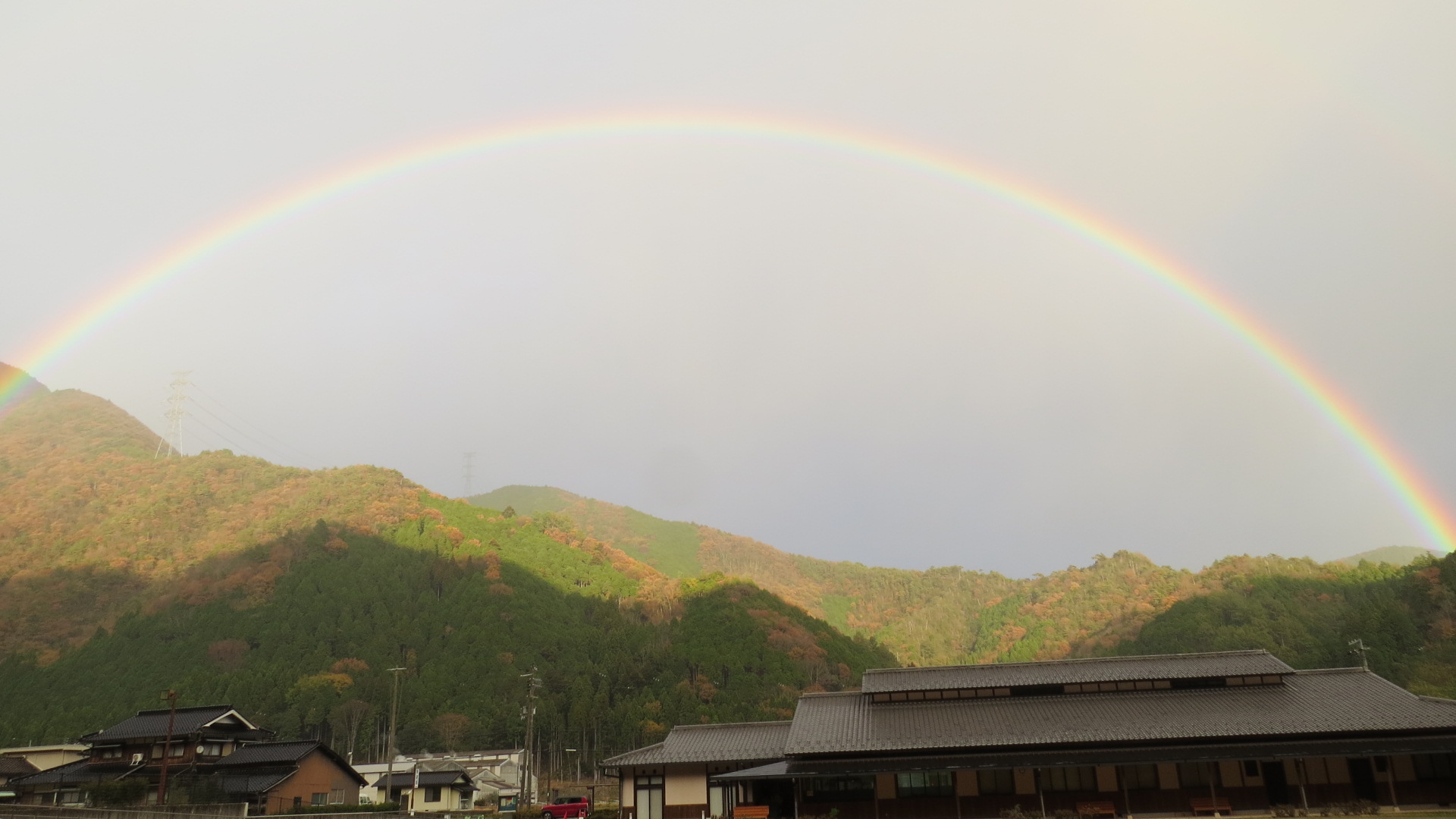 小雨がふる冷え込みがきつい中晴れ間がさして学遊館を虹が包み込む写真