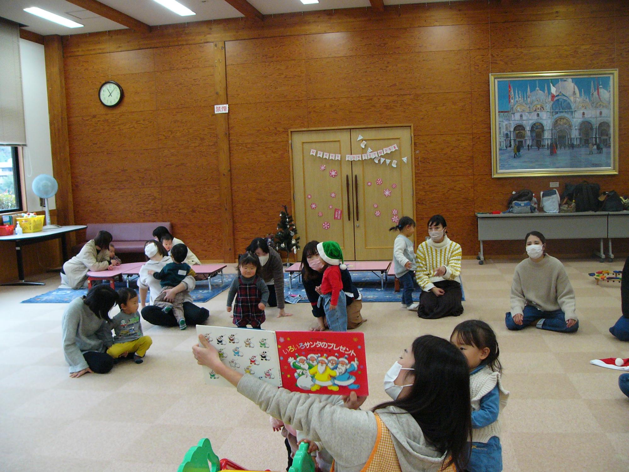 絵本の読み聞かせをしているサポーターさんと喜んで聞いている子どもたちの写真