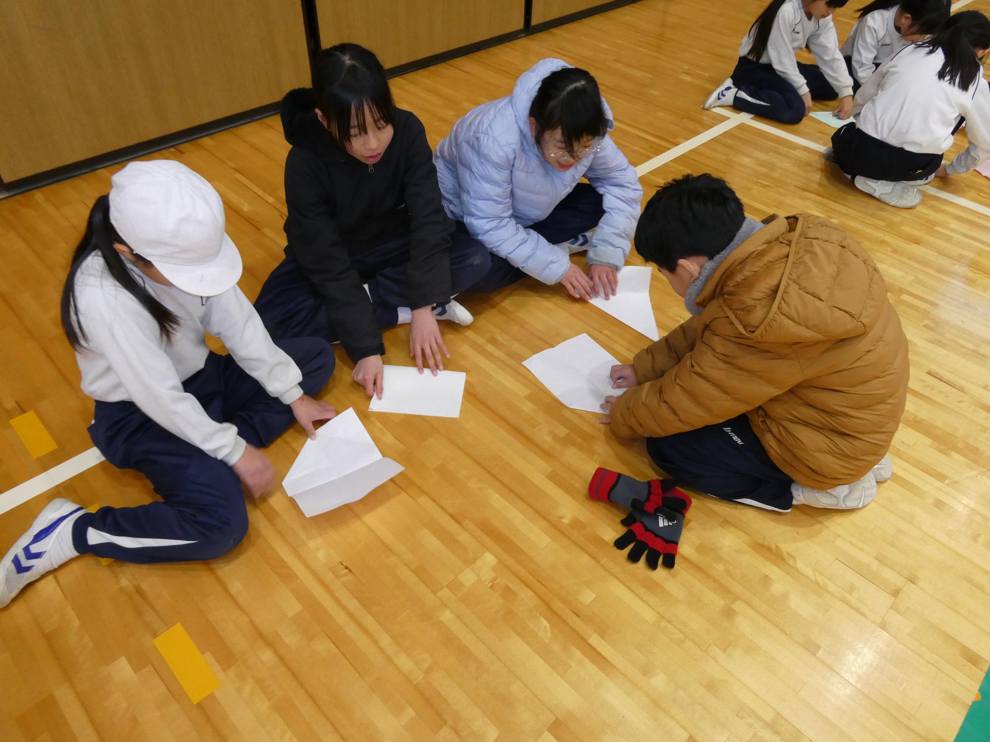 紙飛行機を折る子どもたち