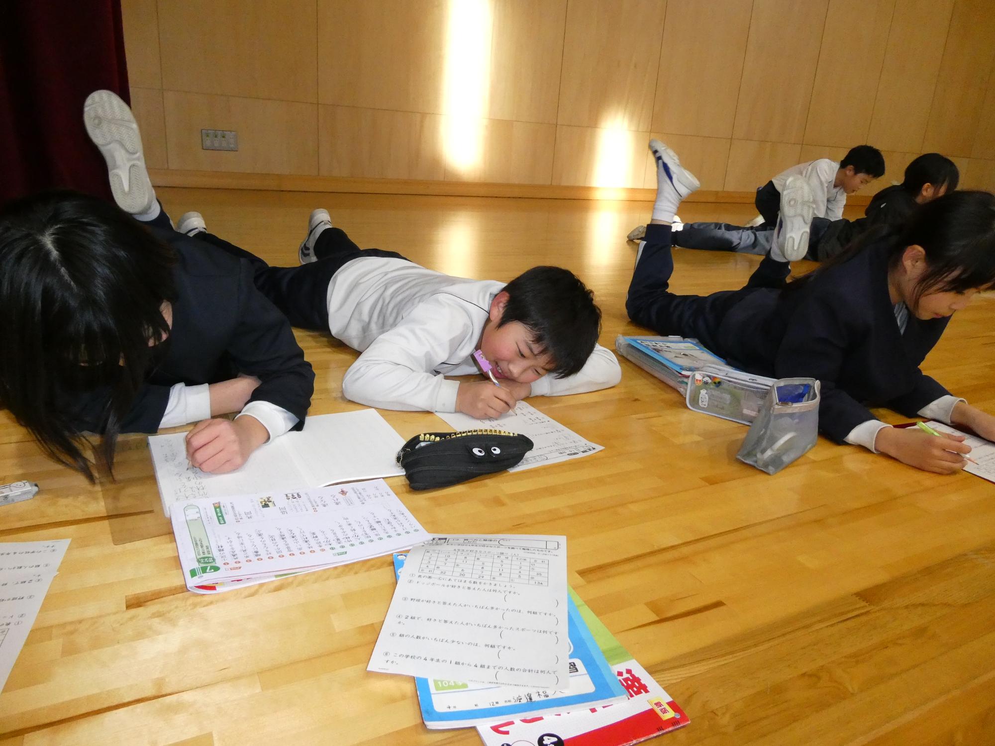 寝転がって宿題をする子どもたち