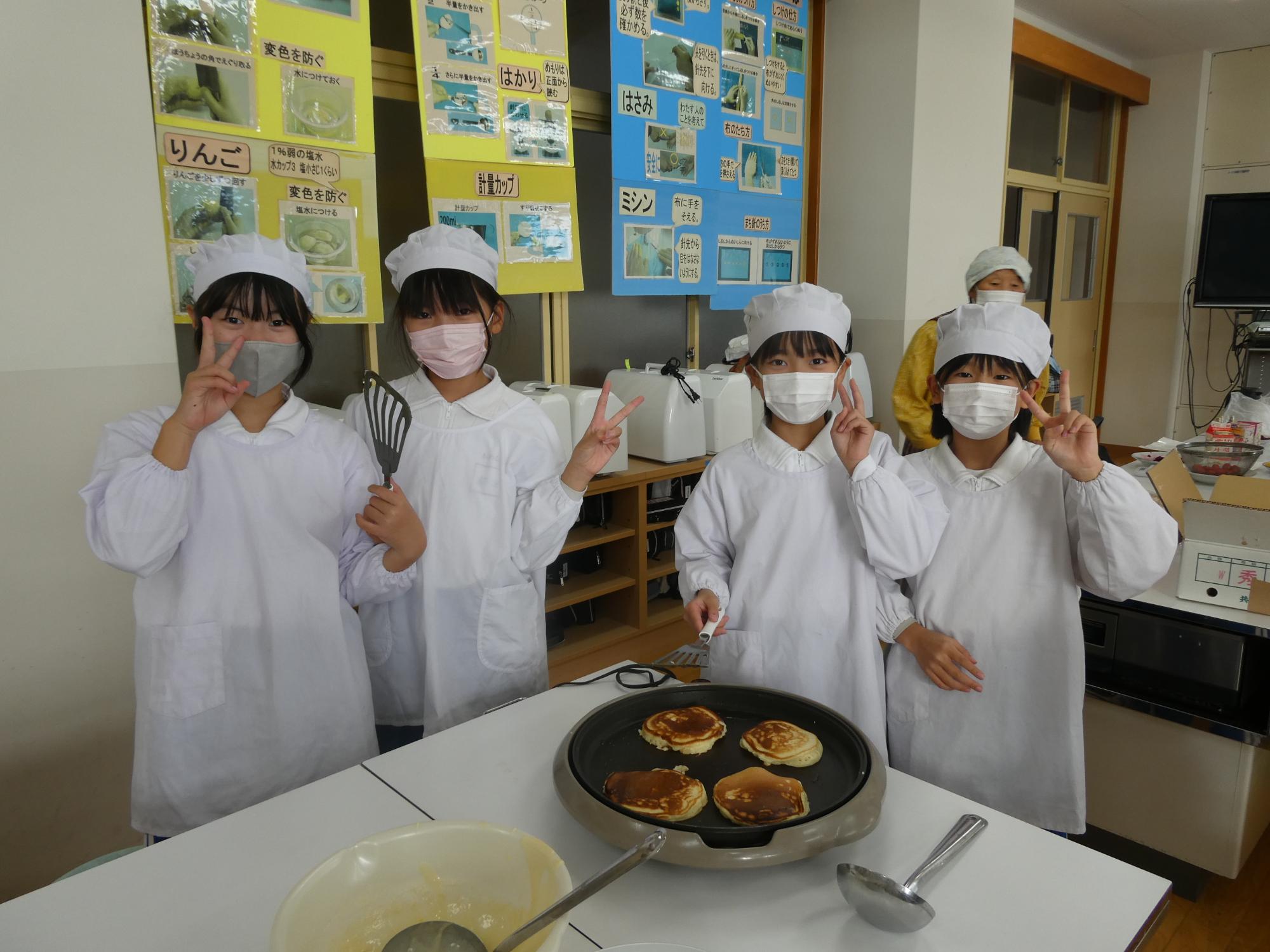パンケーキを焼きながらピースサインをする子どもたち