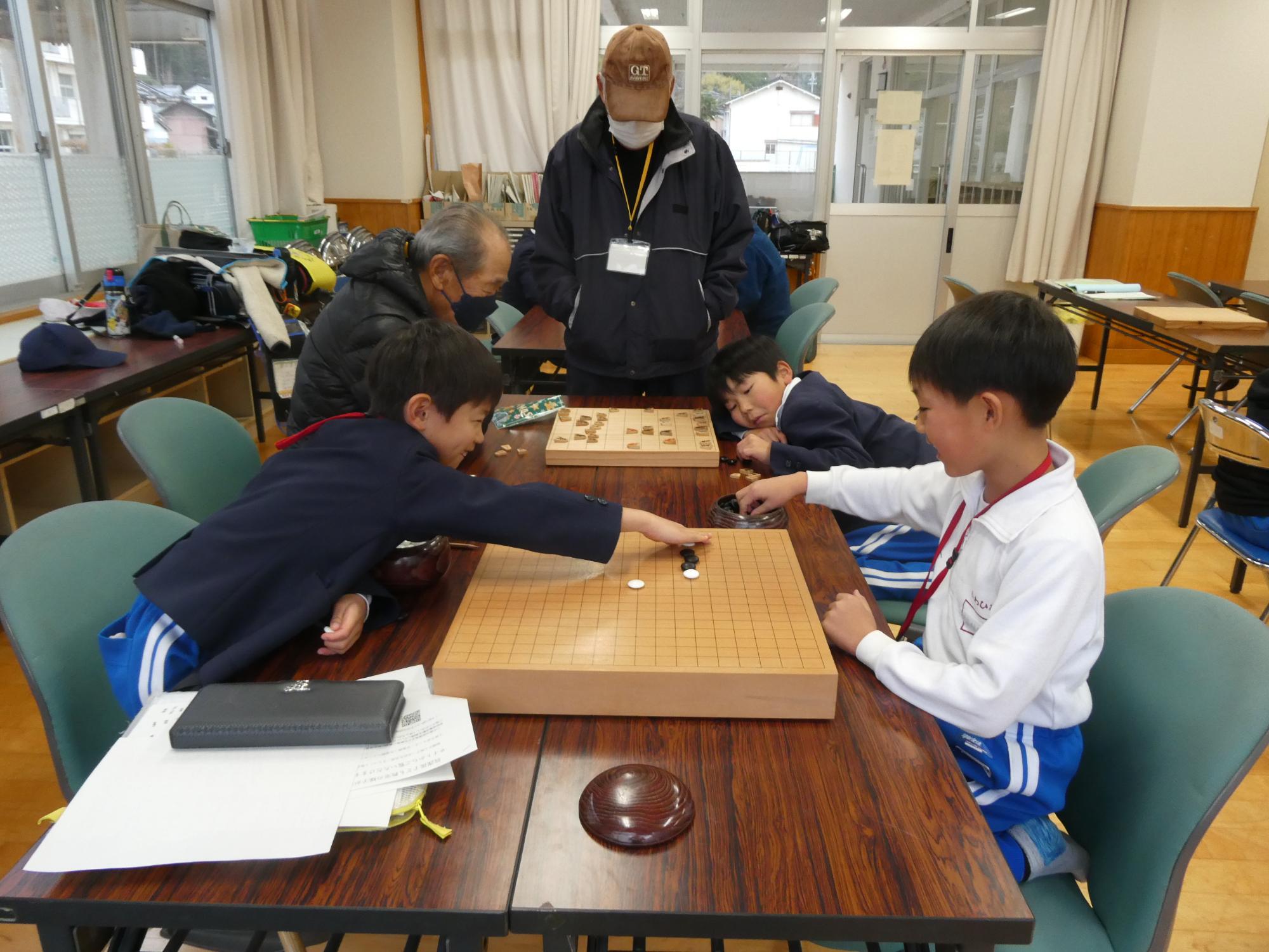 将棋をする子どもと五目並べをする子どもの写真