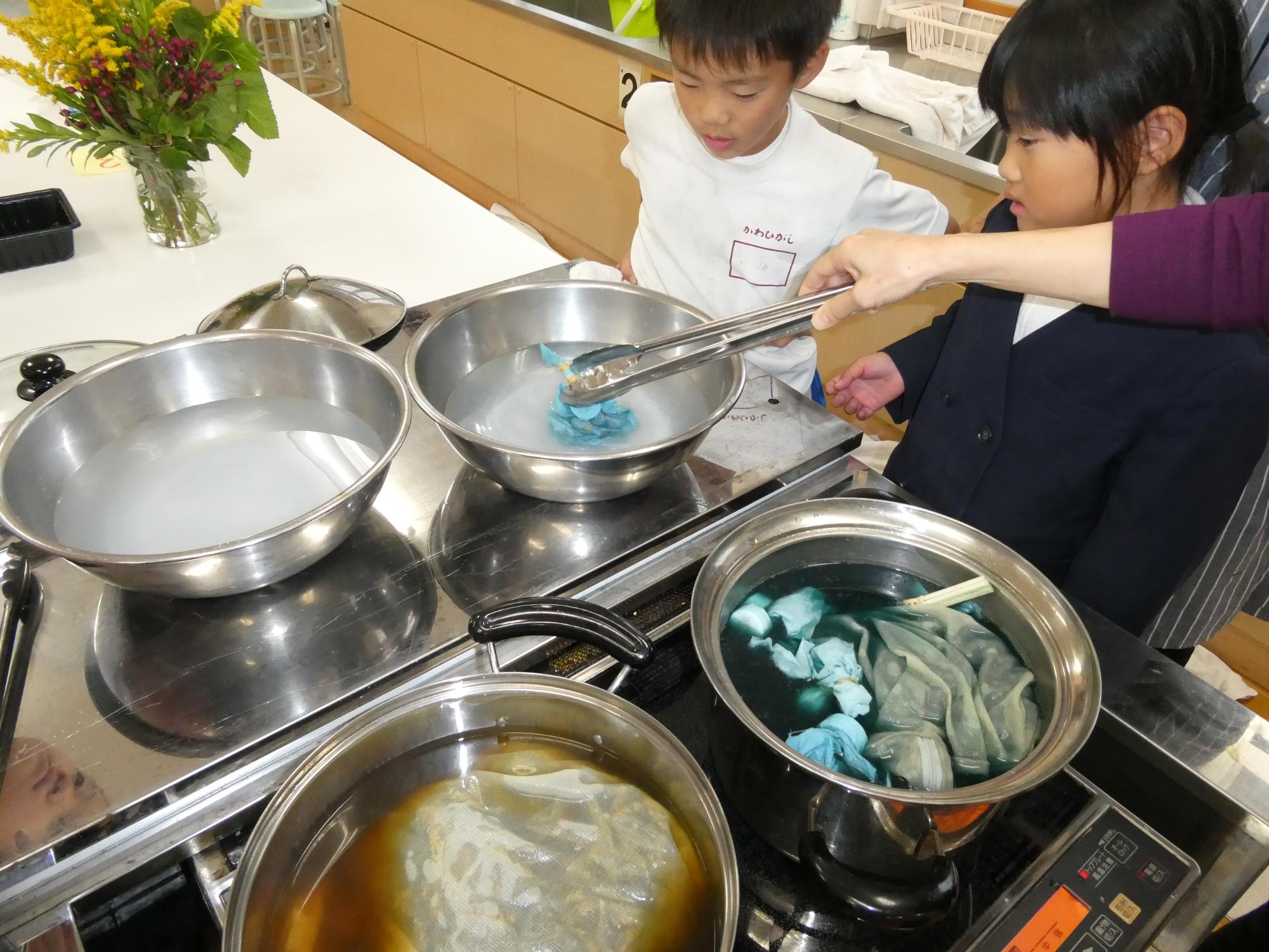 染め上がった布をミョウバン液につけている写真