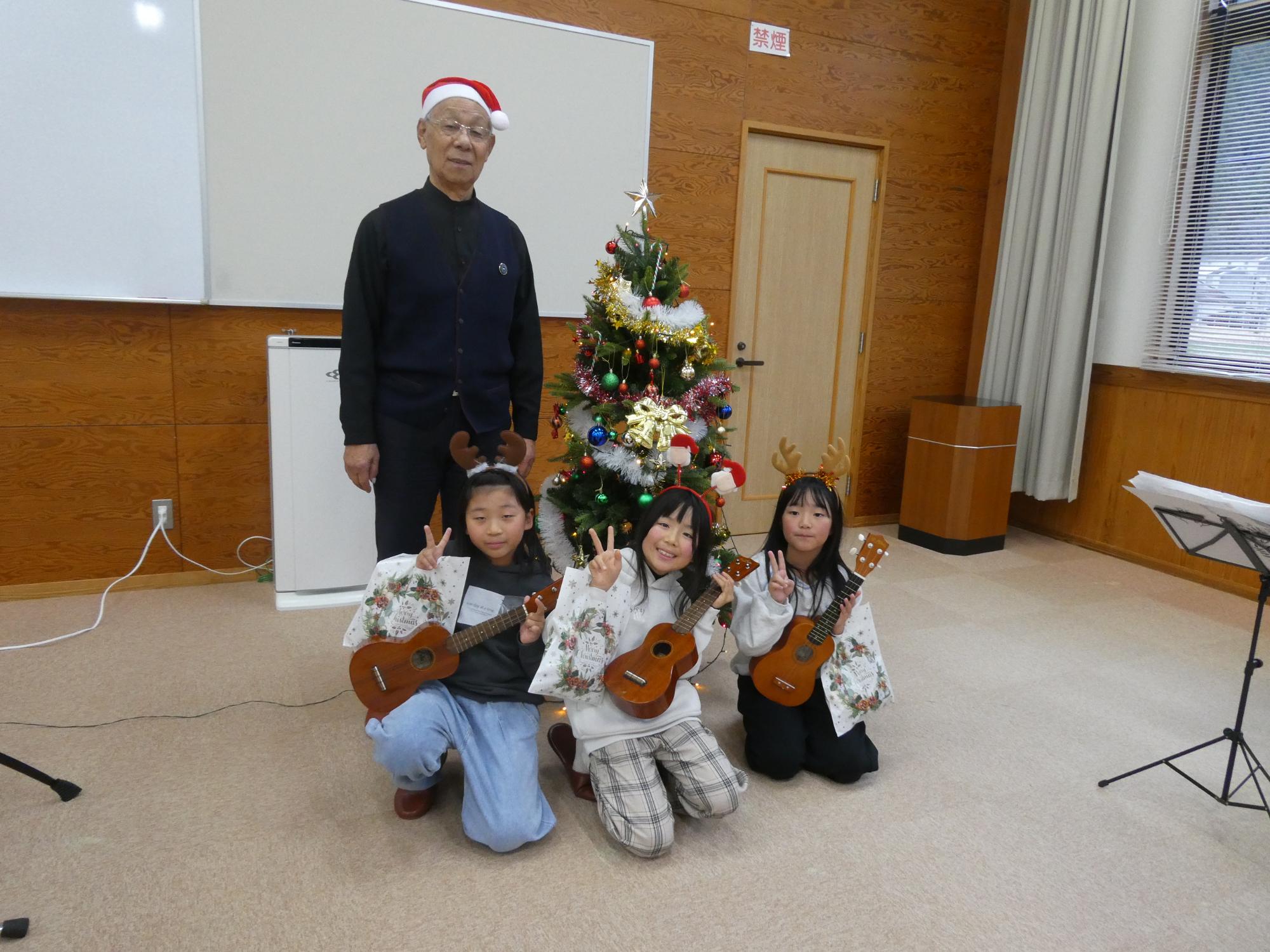 先生とツリーの前でピースサインをする子どもたち