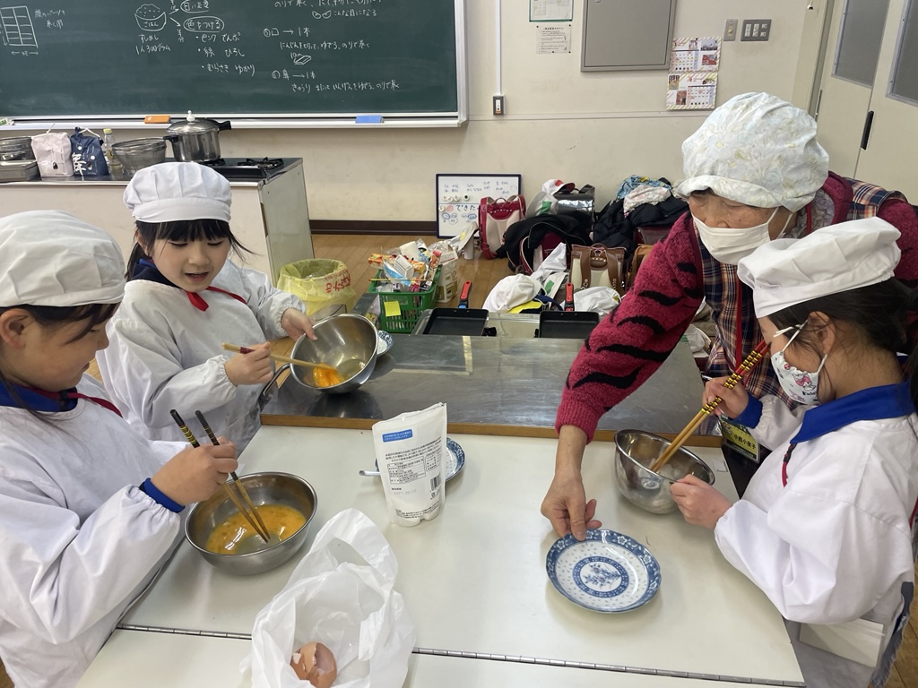 サポーターと厚焼き卵を作る子どもたち