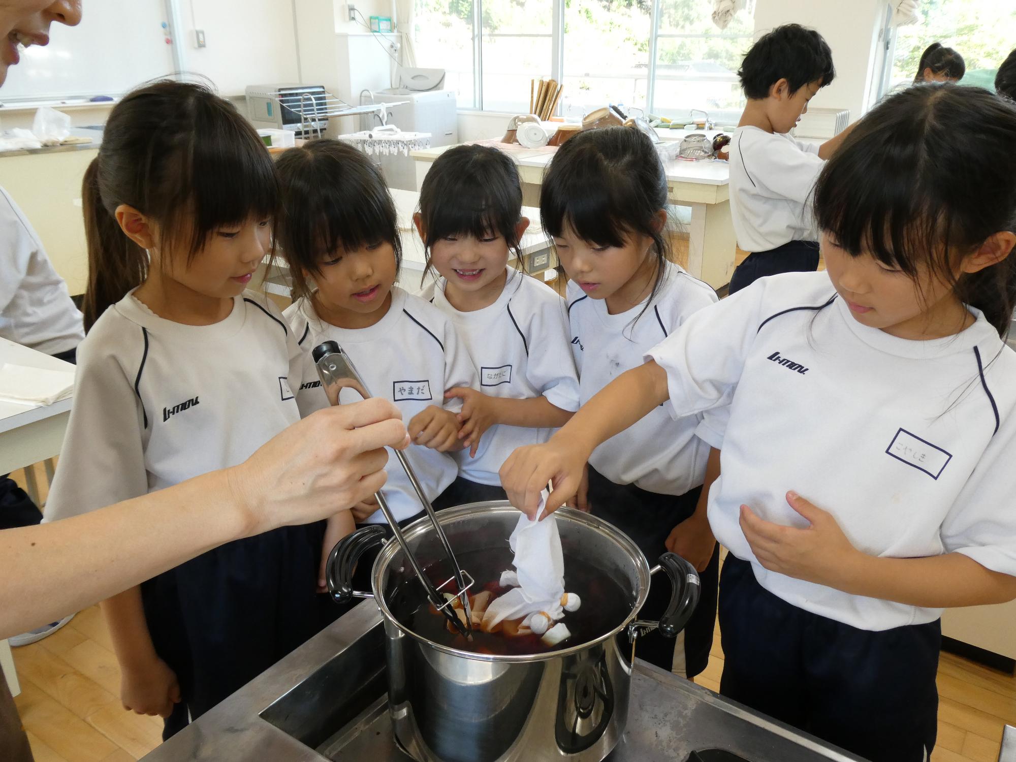 玉ねぎの皮を煮出した鍋に生地を入れる子どもたち