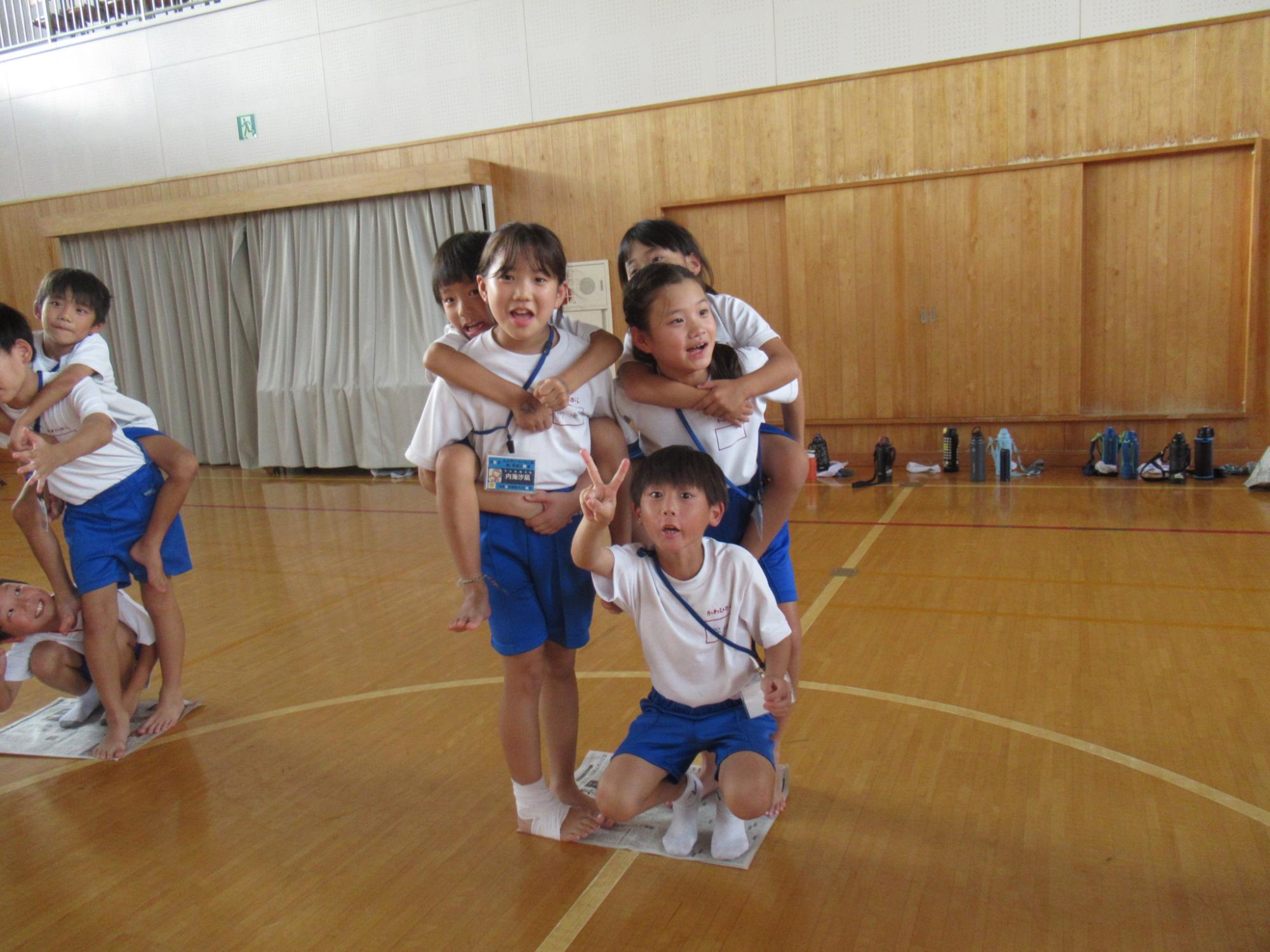 新聞紙からはみ出ないように乗る5人の子どもたち