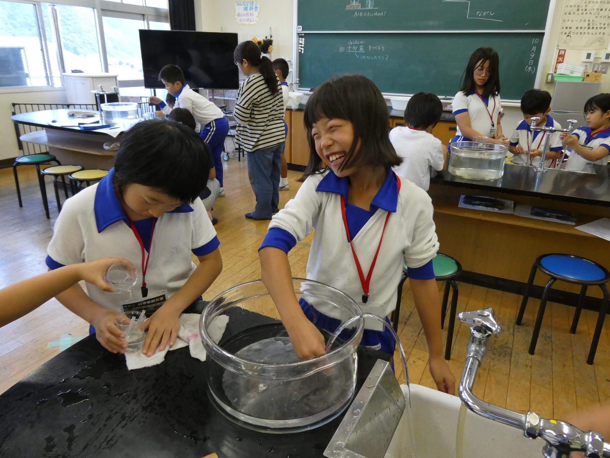 サイフォンの原理の実験をする子どもたち