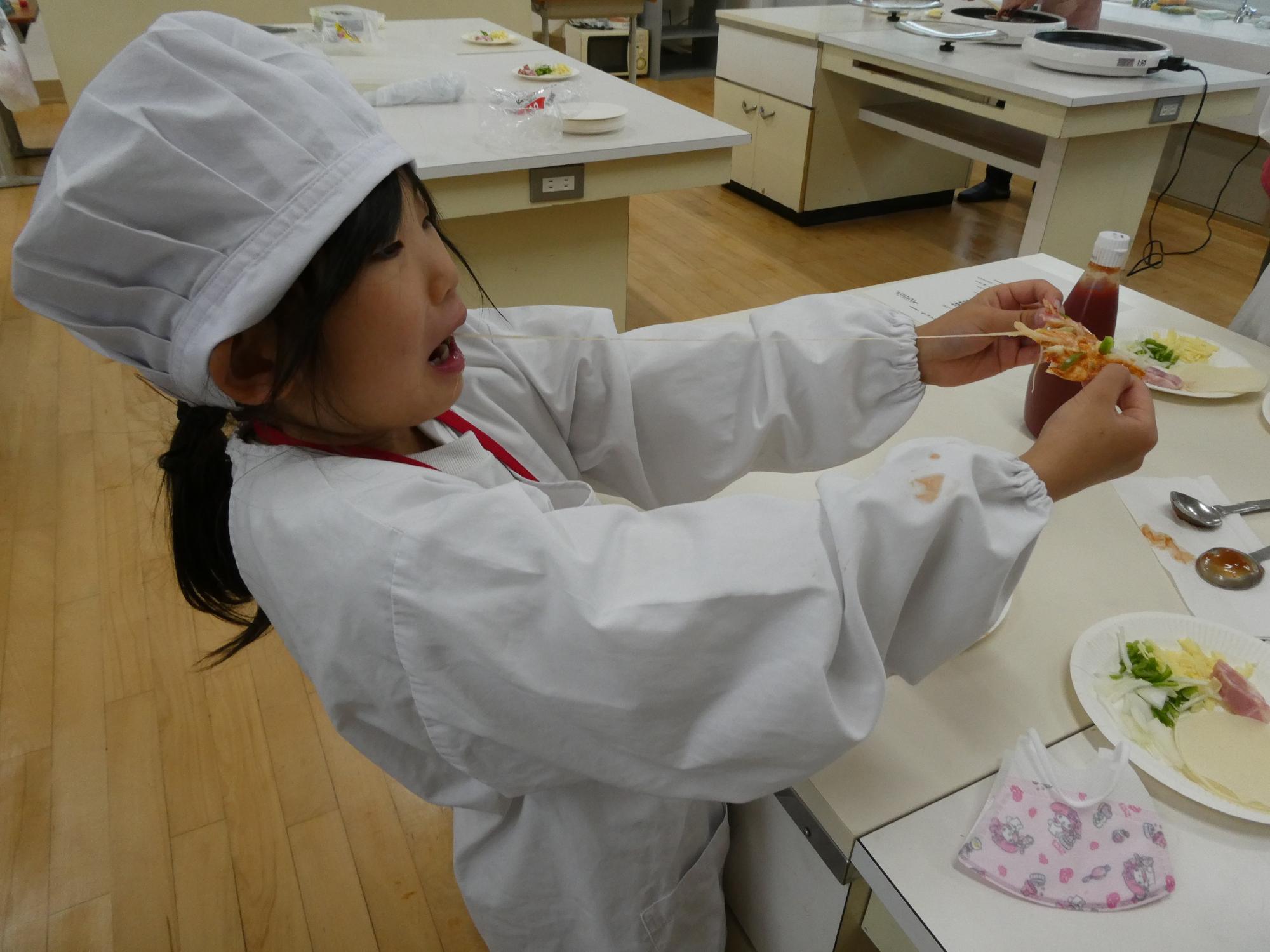 伸びたチーズを食べる子ども