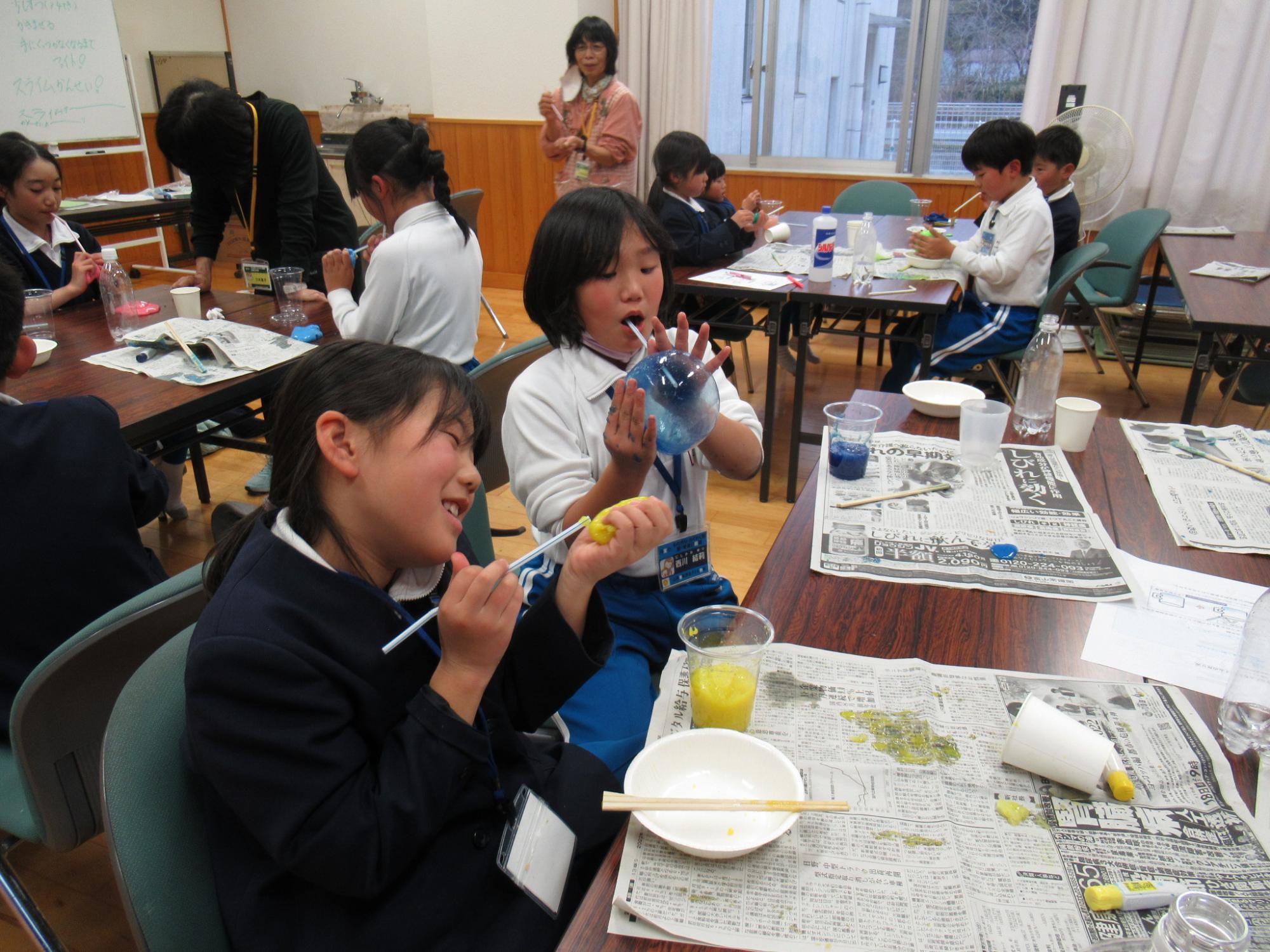 参加している2人の女の子がカラフルに色付けした自作スライムで遊んでいる写真