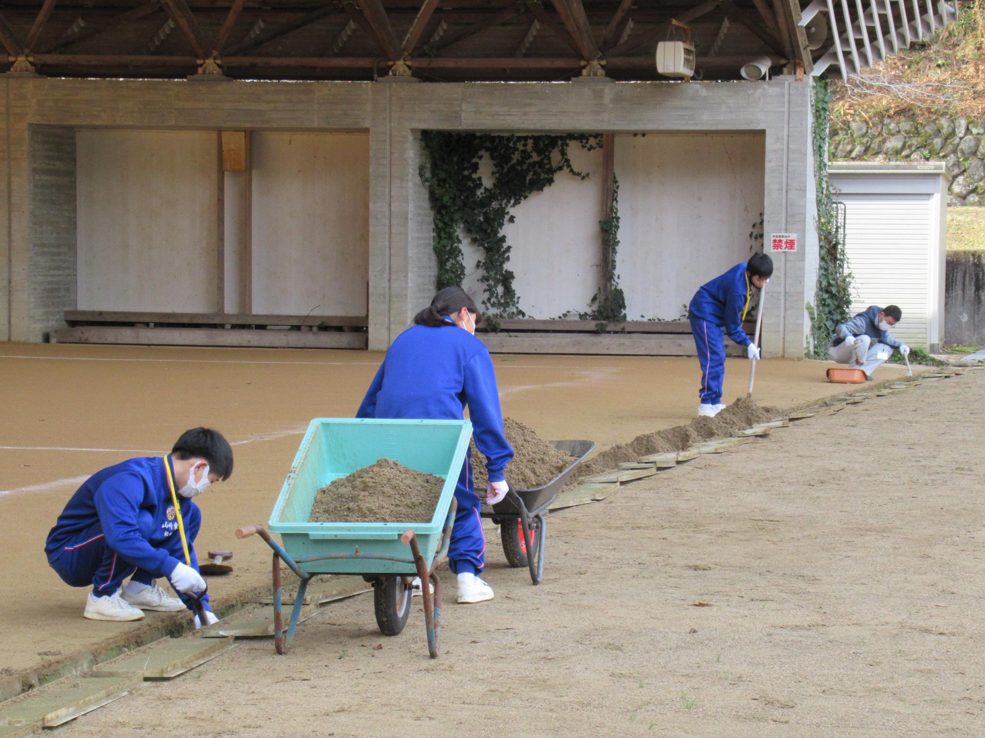 溝にたまった土を一生懸命掃除しているトライやるの児童の写真