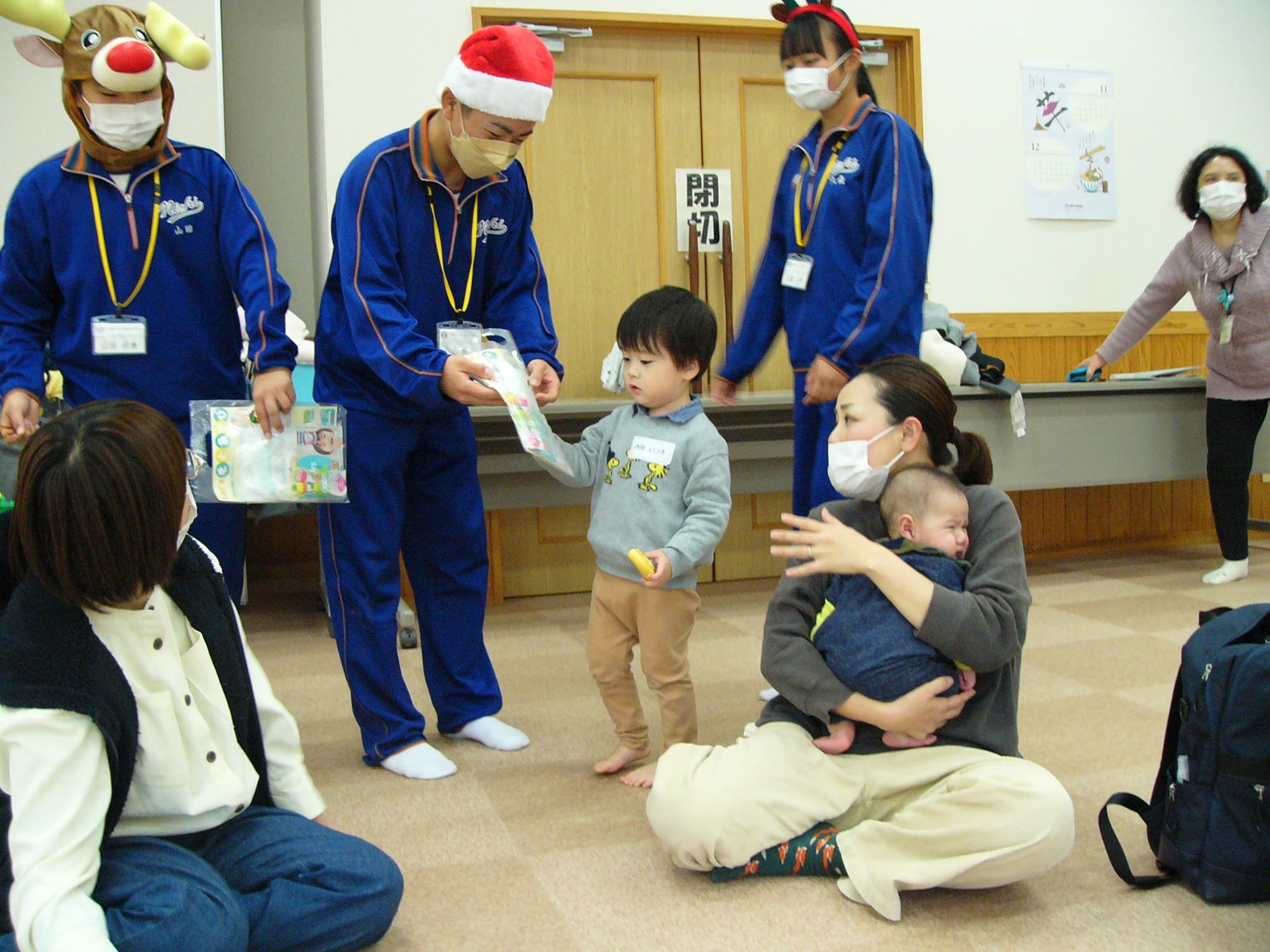 親子活動に参加して、クリスマスプレゼントを渡すトライやる生徒らの写真