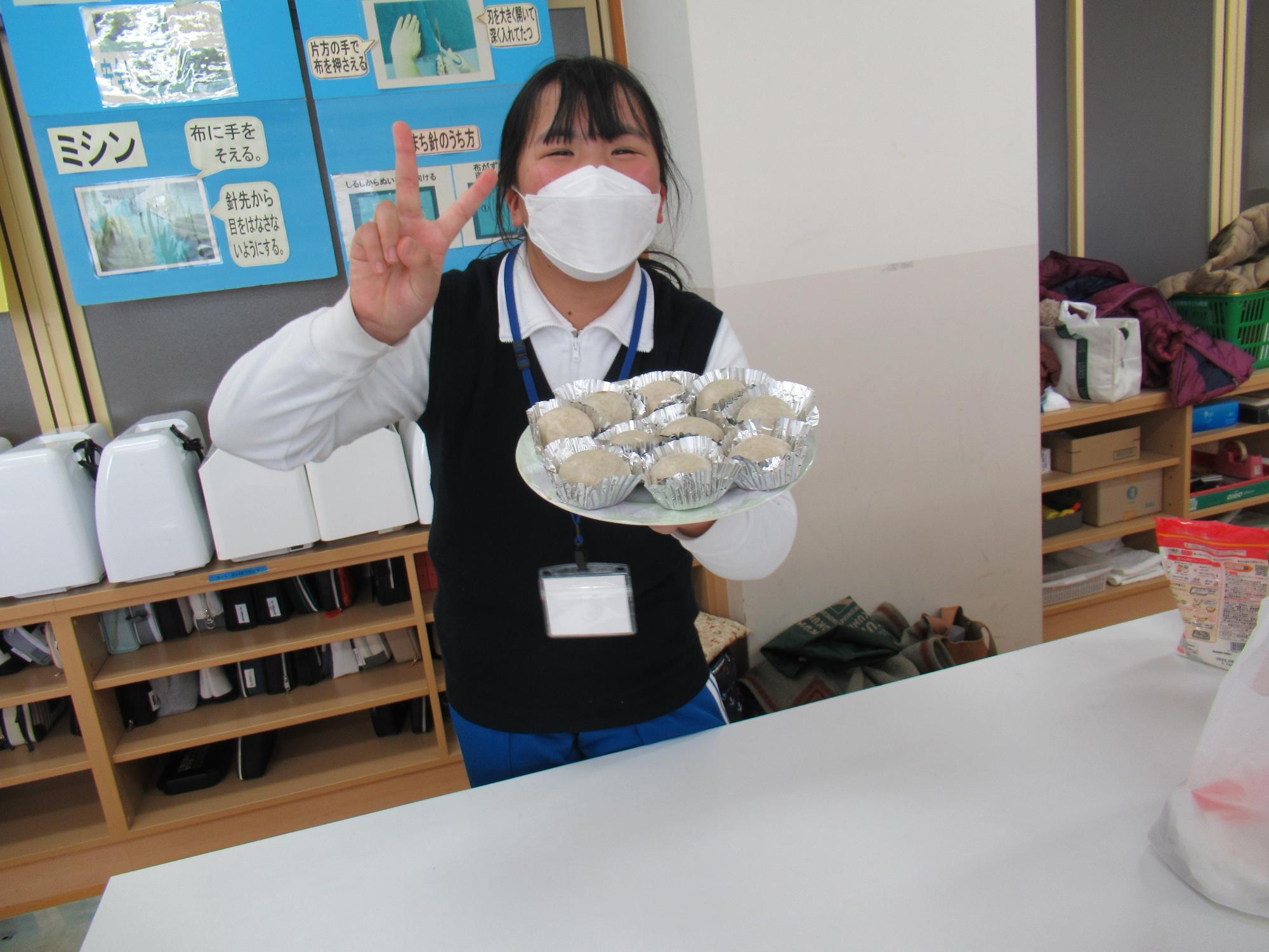 皿一杯のしょうゆまんじゅうを持ってピースサインをする参加者