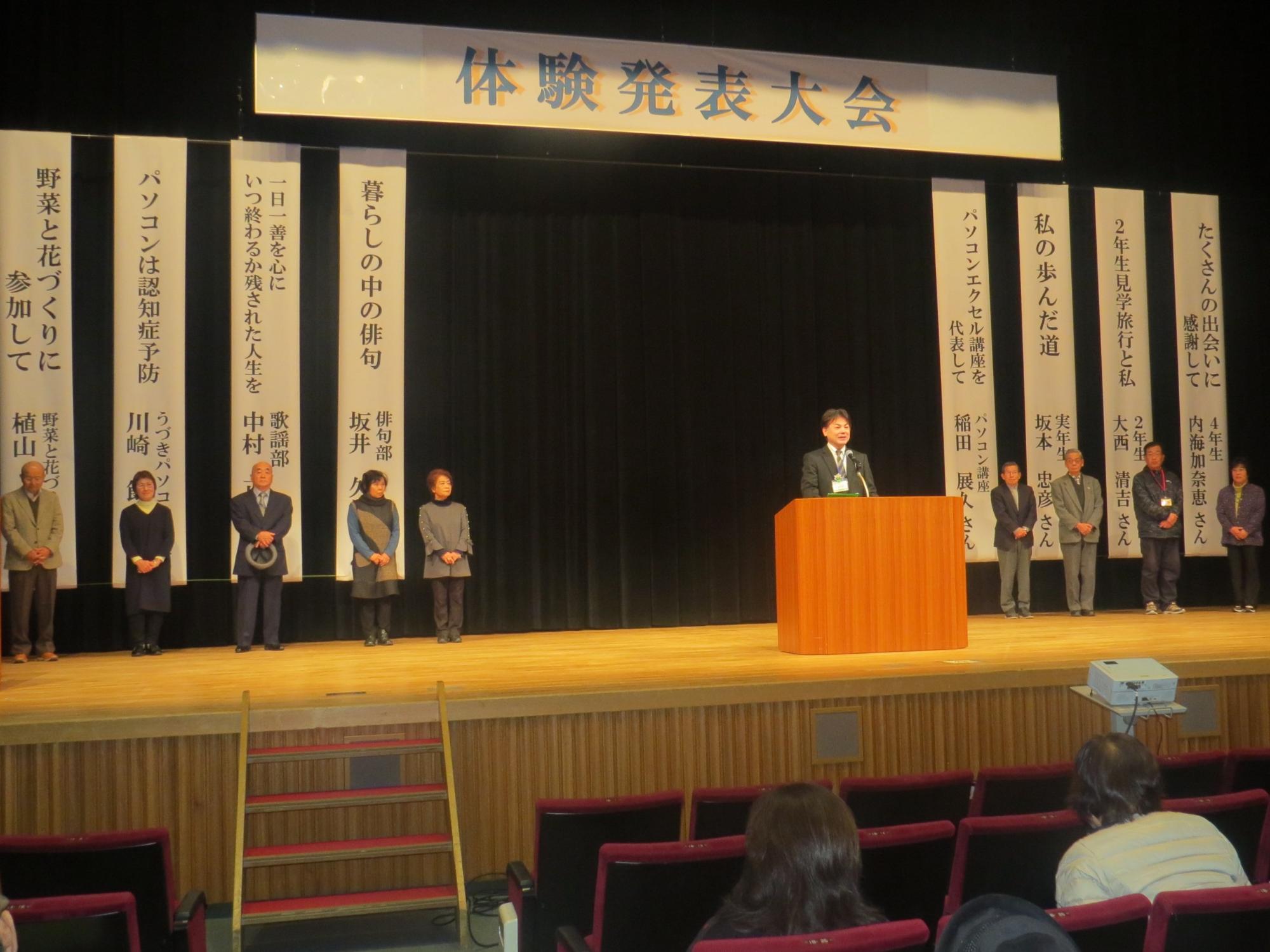 壇上で発表者全員が並び、中央で学遊館館長が話をしている写真