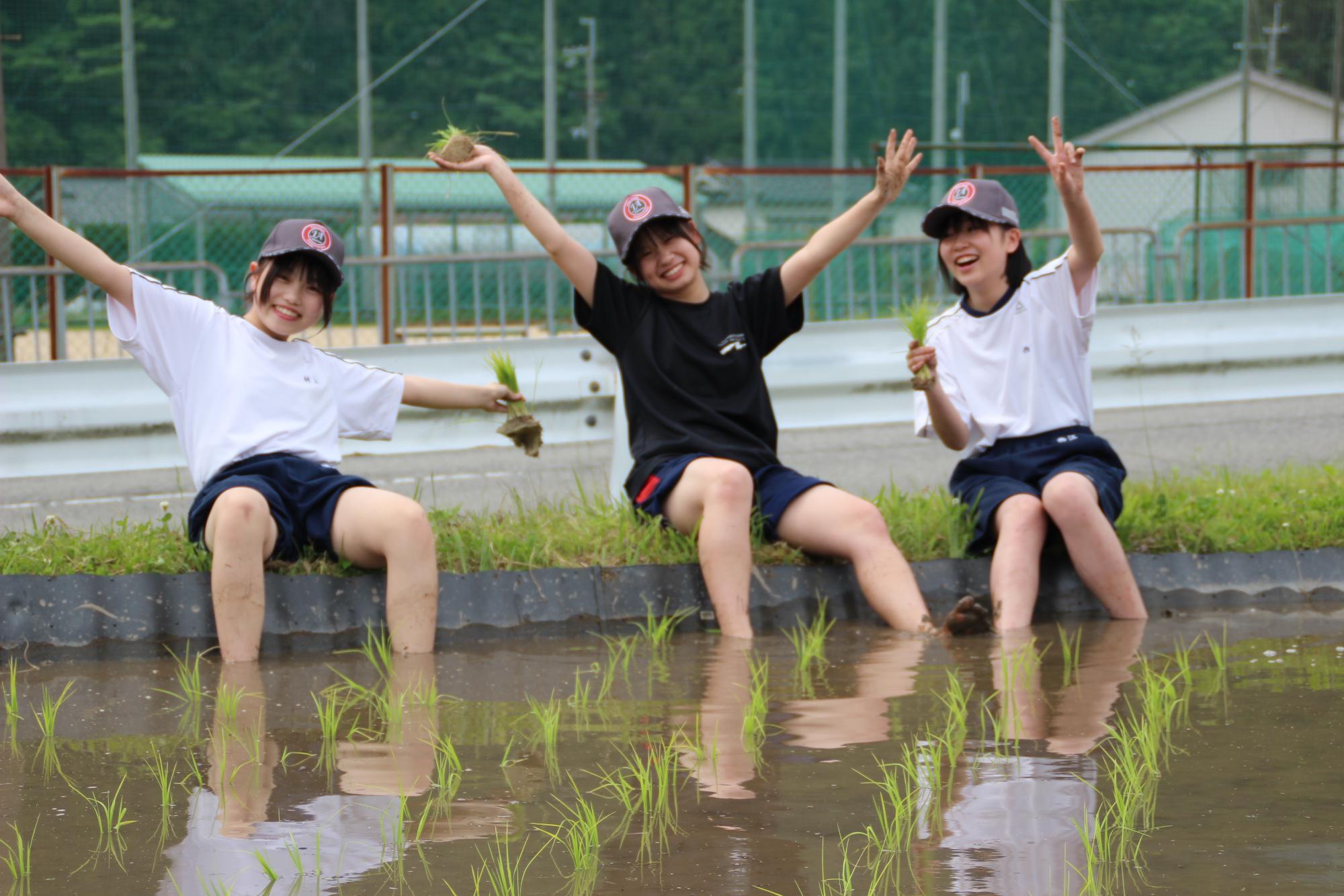 田植えの合間の休憩中に手を振る生徒たち