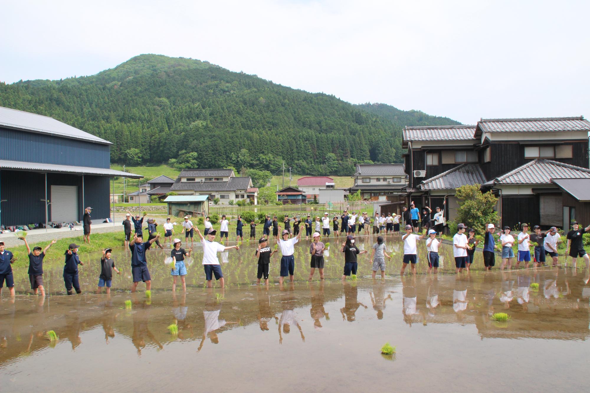 田んぼの周りに集まって手を振る生徒たち