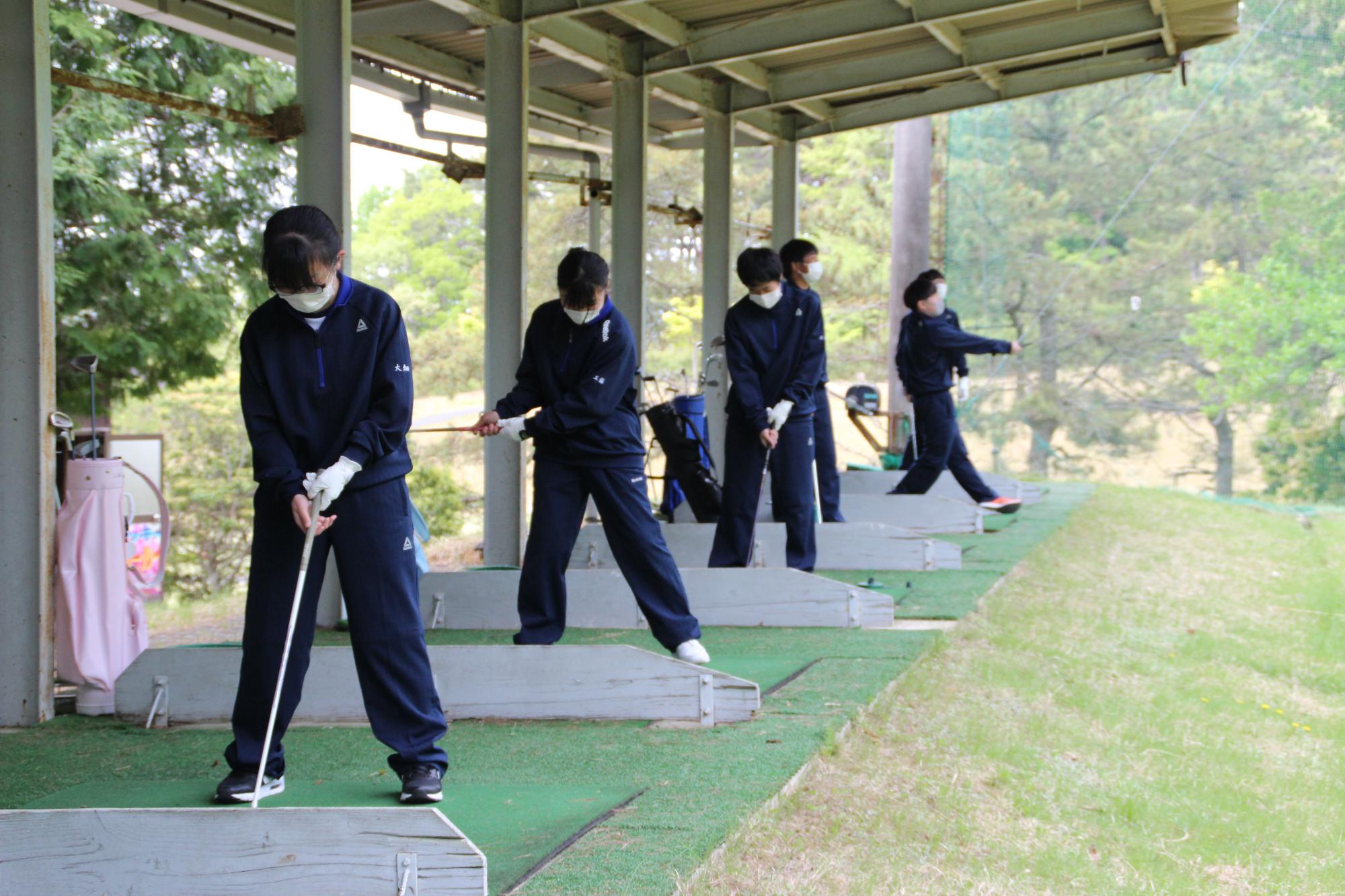 千草カントリークラブの練習場で、アイアンを使って練習する高校生の様子