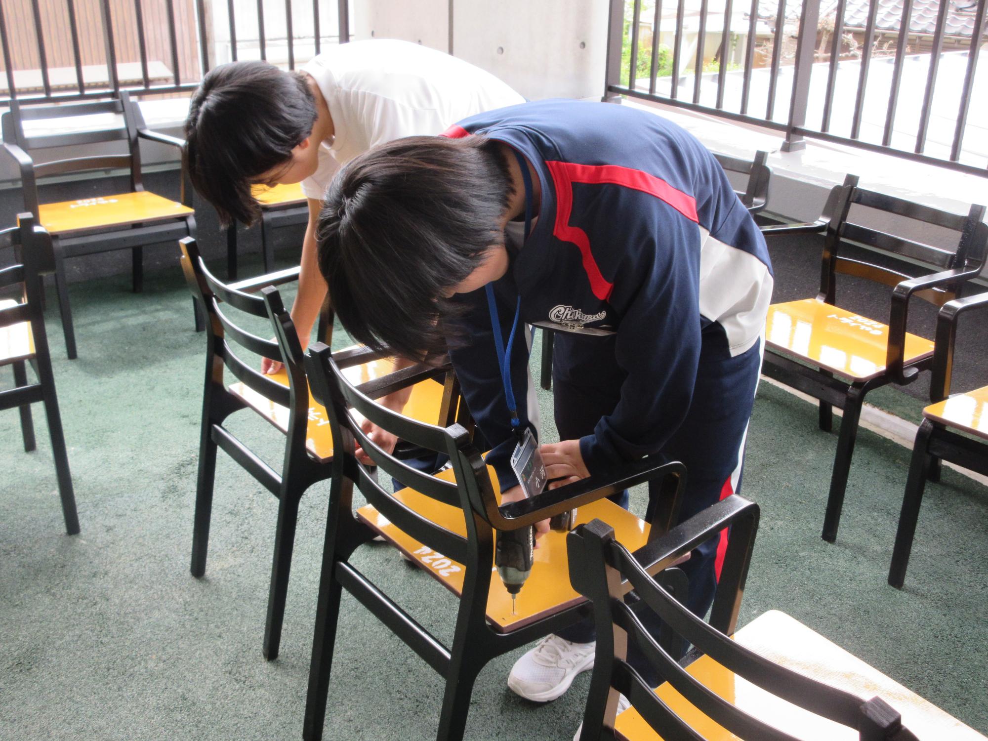 千種中学校2年生の2人が電動ドライバーを使って椅子にビスを打ち混んでいる写真