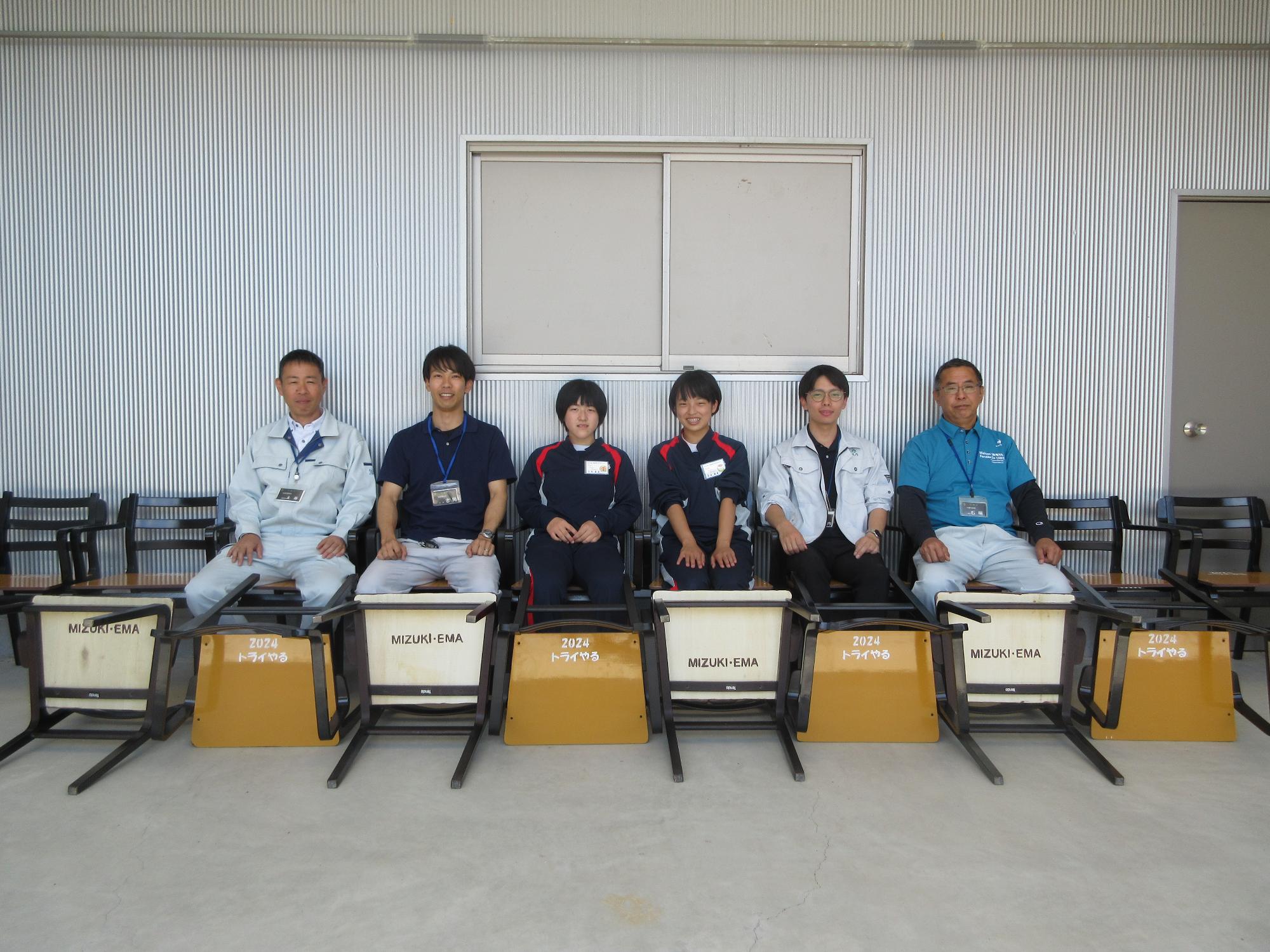 制作した椅子に座っている関係者らの集合写真