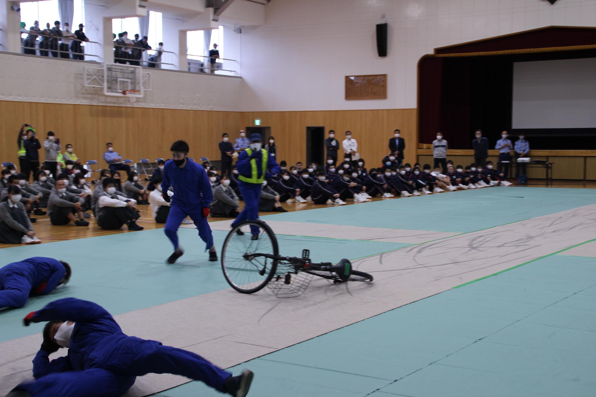 自転車同士の接触事故実演で体を投げ出されて痛がるスタントマンの写真