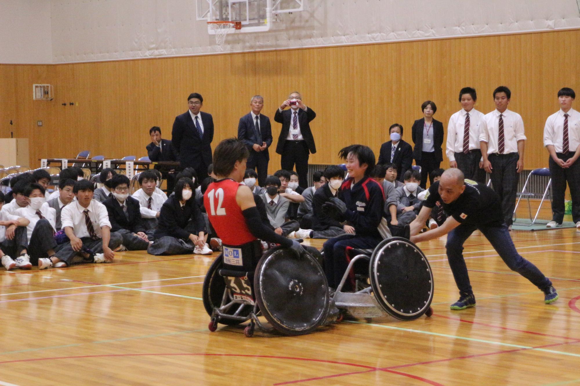 車いす同士で正面からぶつかり、車いすラグビーでルールとして認められているタックルを生徒が体験している写真