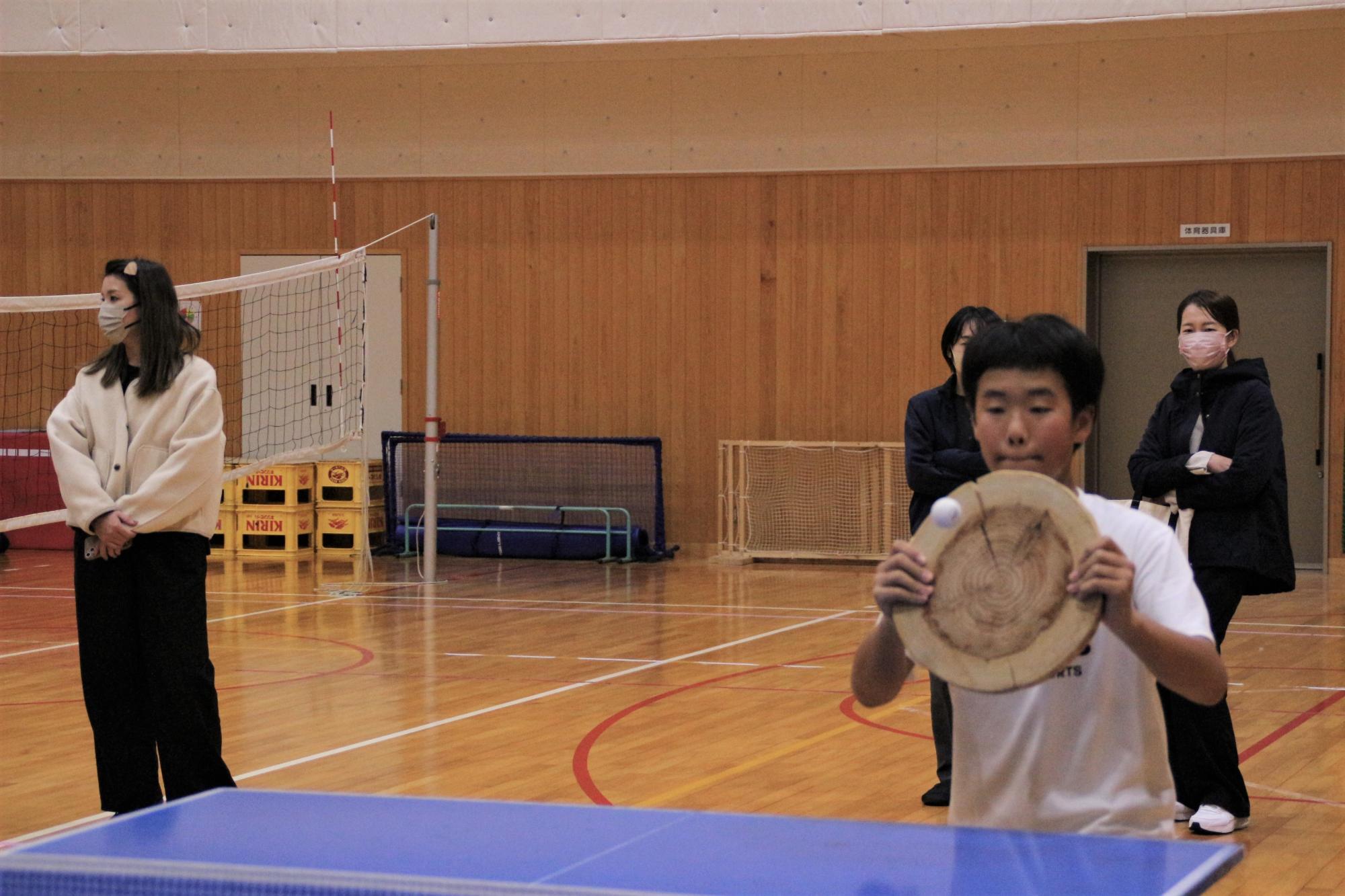 両手で丸太をもち、真剣な顔つきで小学生が球を返そうとしている写真