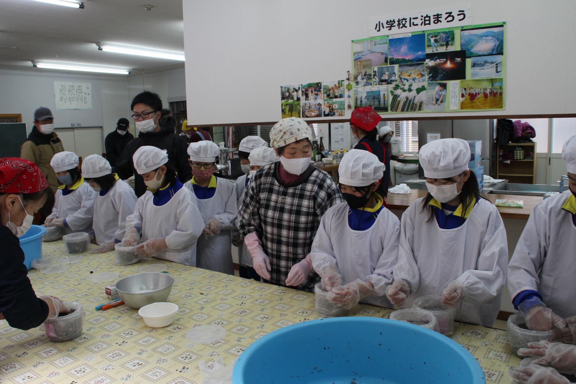 混ぜ合わせた味噌を容器に詰めている児童らの写真