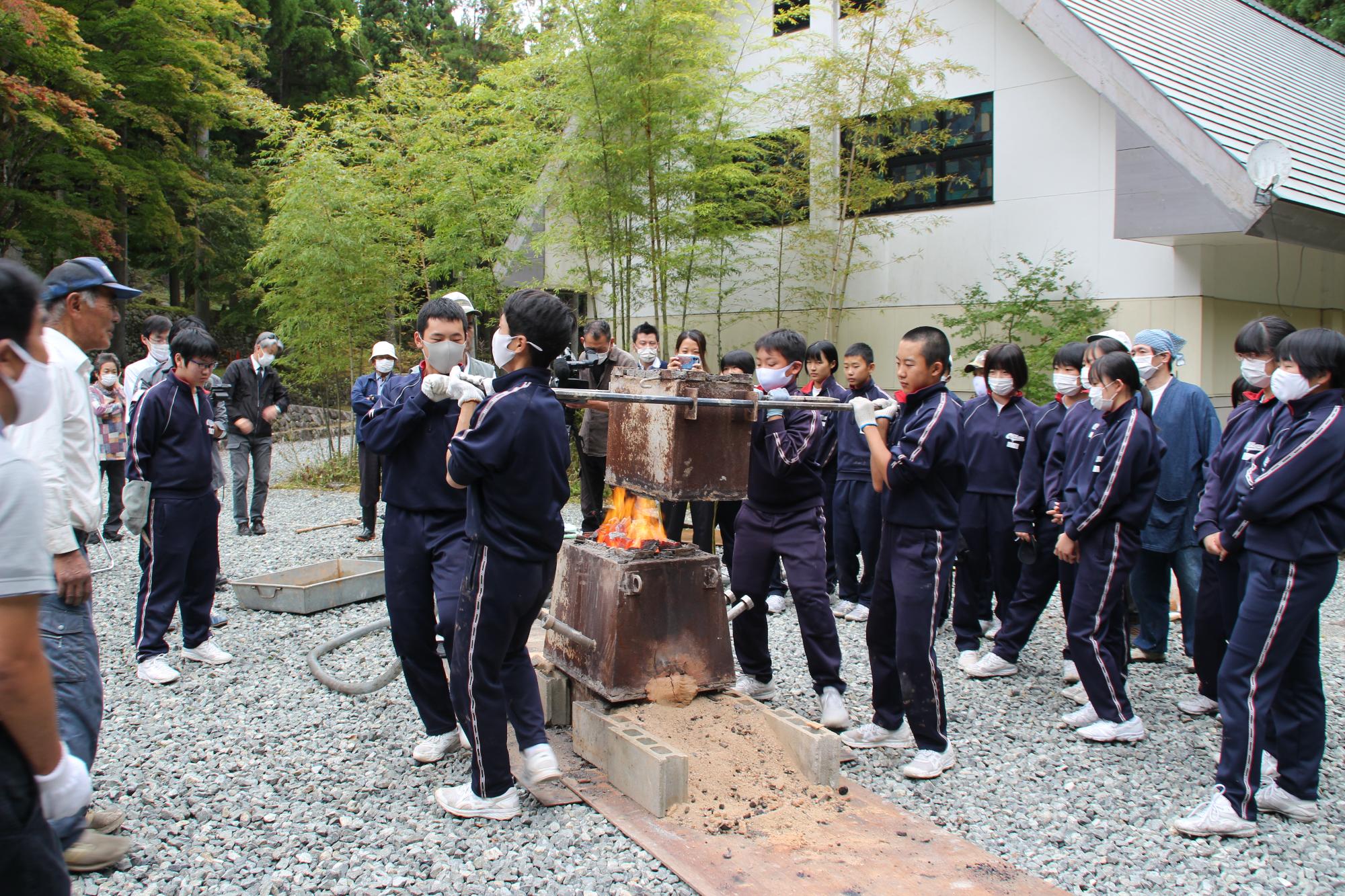 溶鉱炉を数人で持ち上げて、溶鉱炉を解体させている中学生の写真