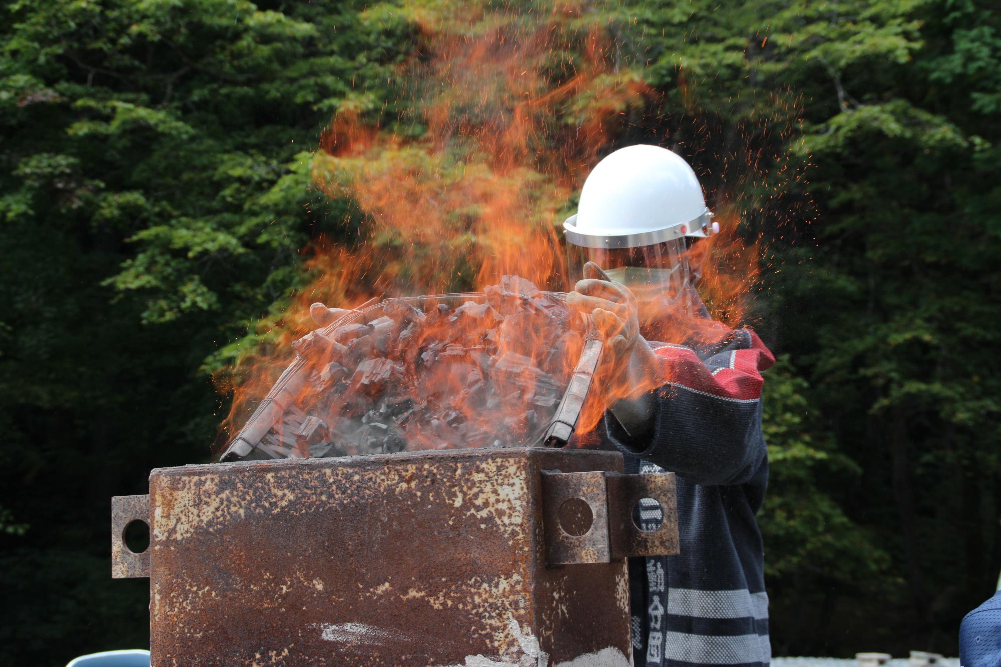 木炭を炉に投入する中学生の写真