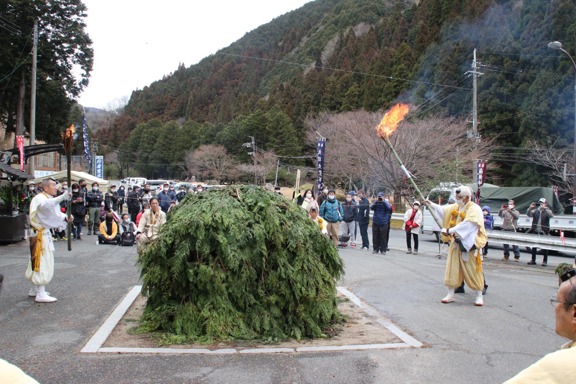 山伏がトンドに火入れしようとしている写真