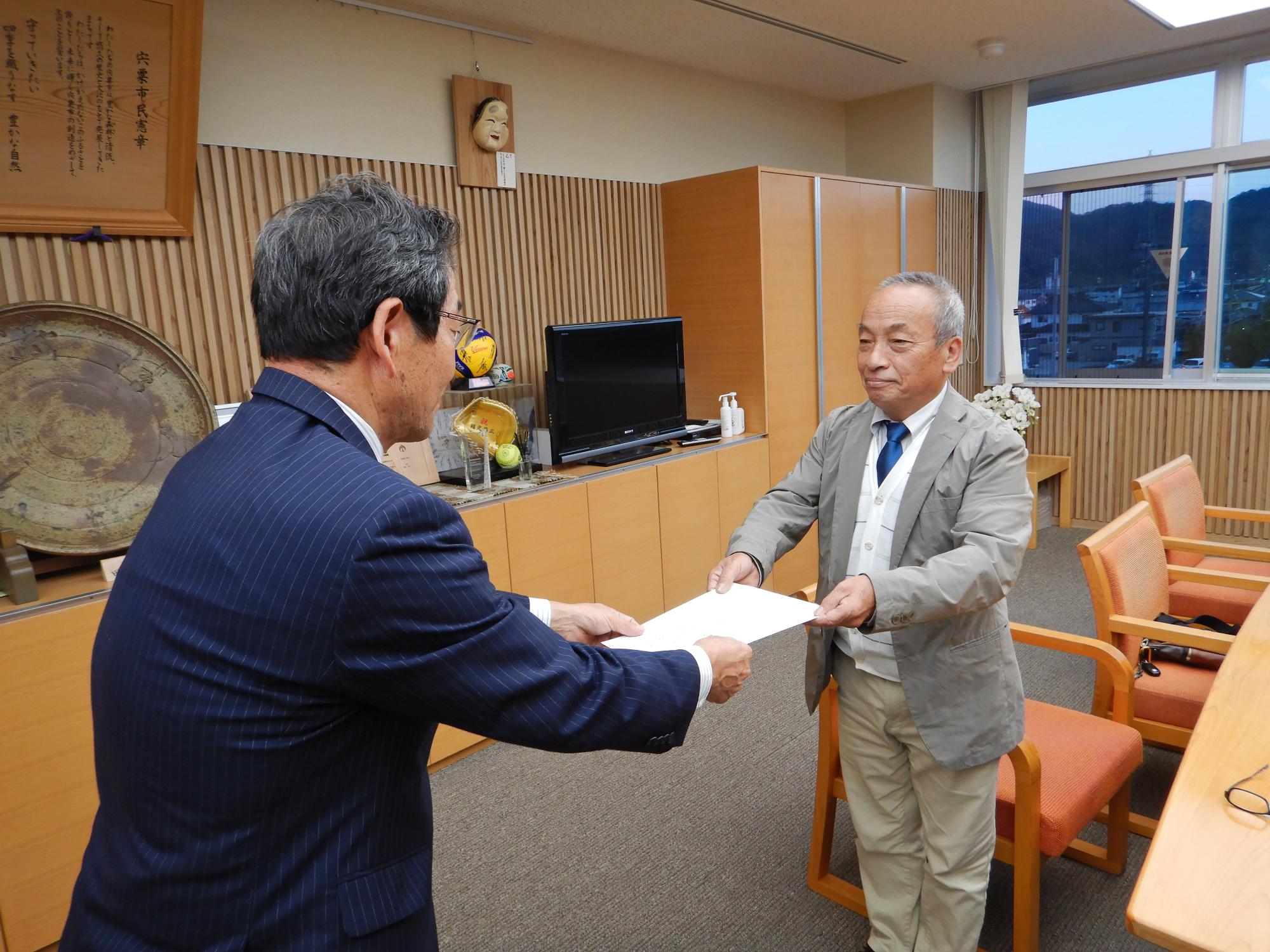 審議会の小林会長が答申書を福元市長に手渡している写真