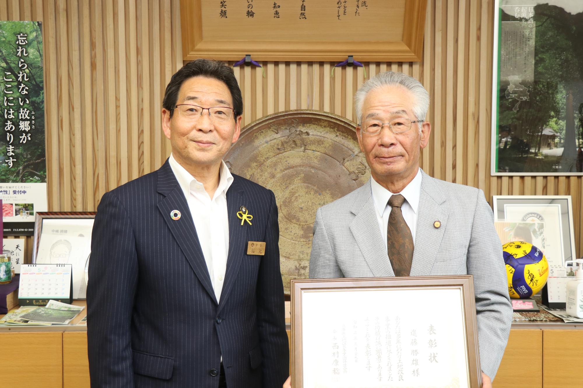 土地改良事業功労者表彰受賞報告、左に福元市長、右に表彰状を手にした進藤さんが並んでいる写真