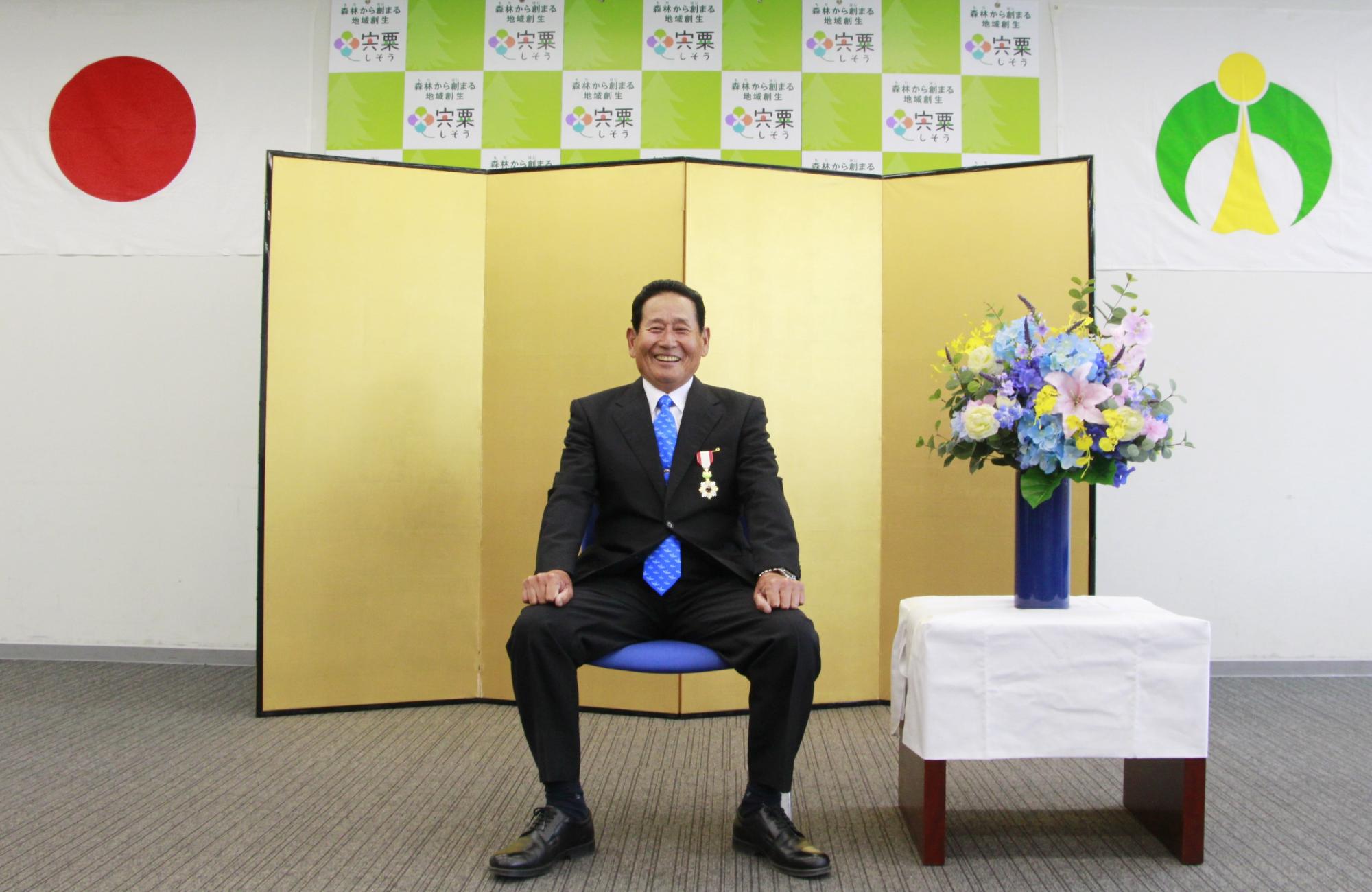 令和3年春叙勲を受章された小林健志さんが椅子に座っている写真