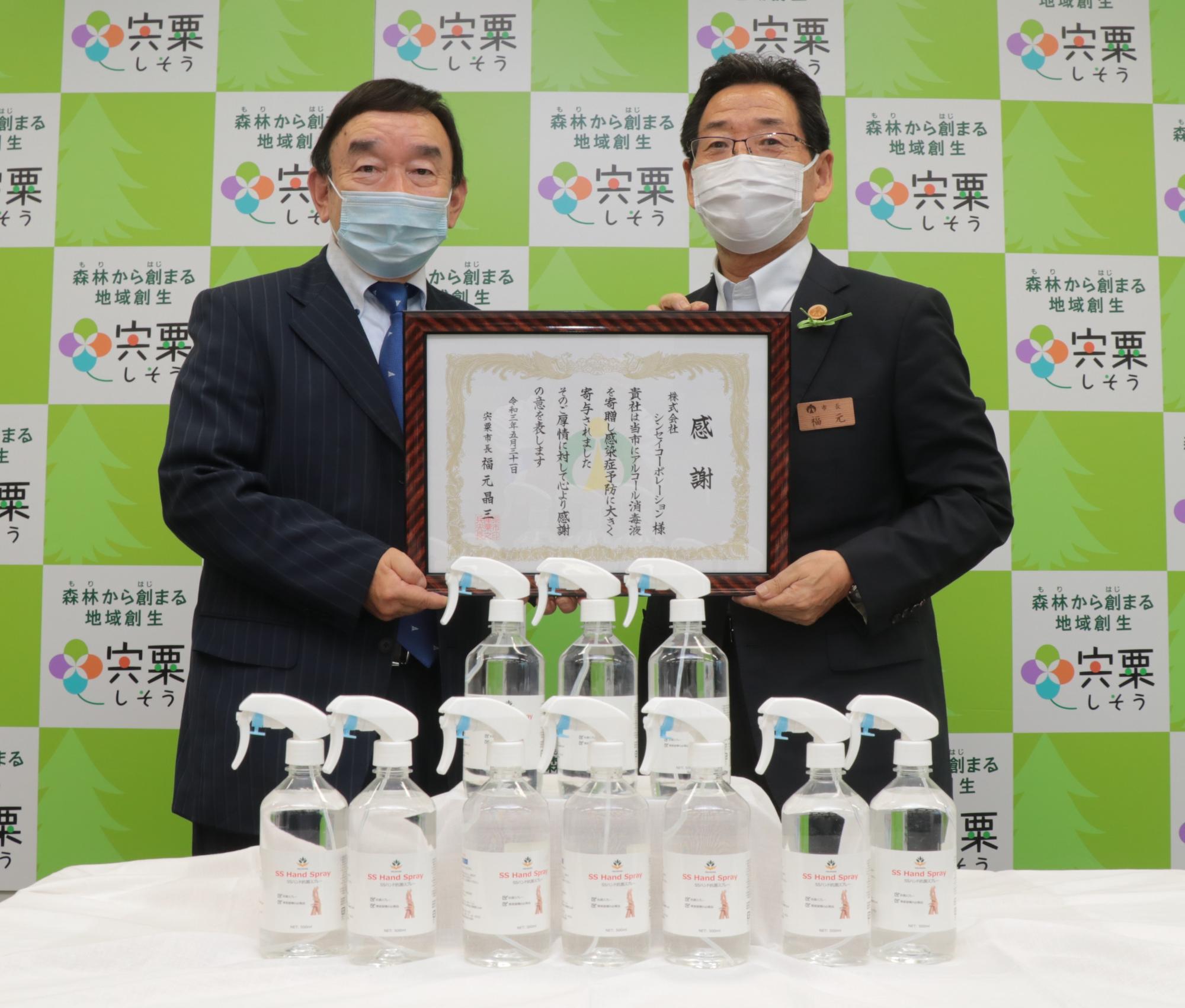 左は感謝状を手にした代表取締役会長の大東敏郎様、右は福元市長の写真