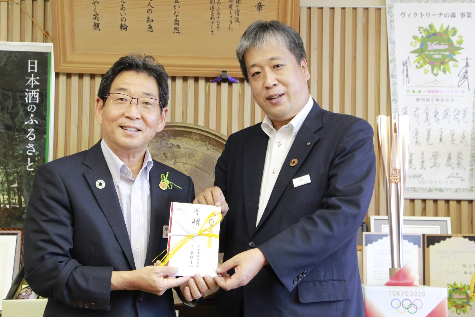 左、西兵庫信用金庫本店の渋谷営業部長から寄付を受け取る、右、福元市長の写真
