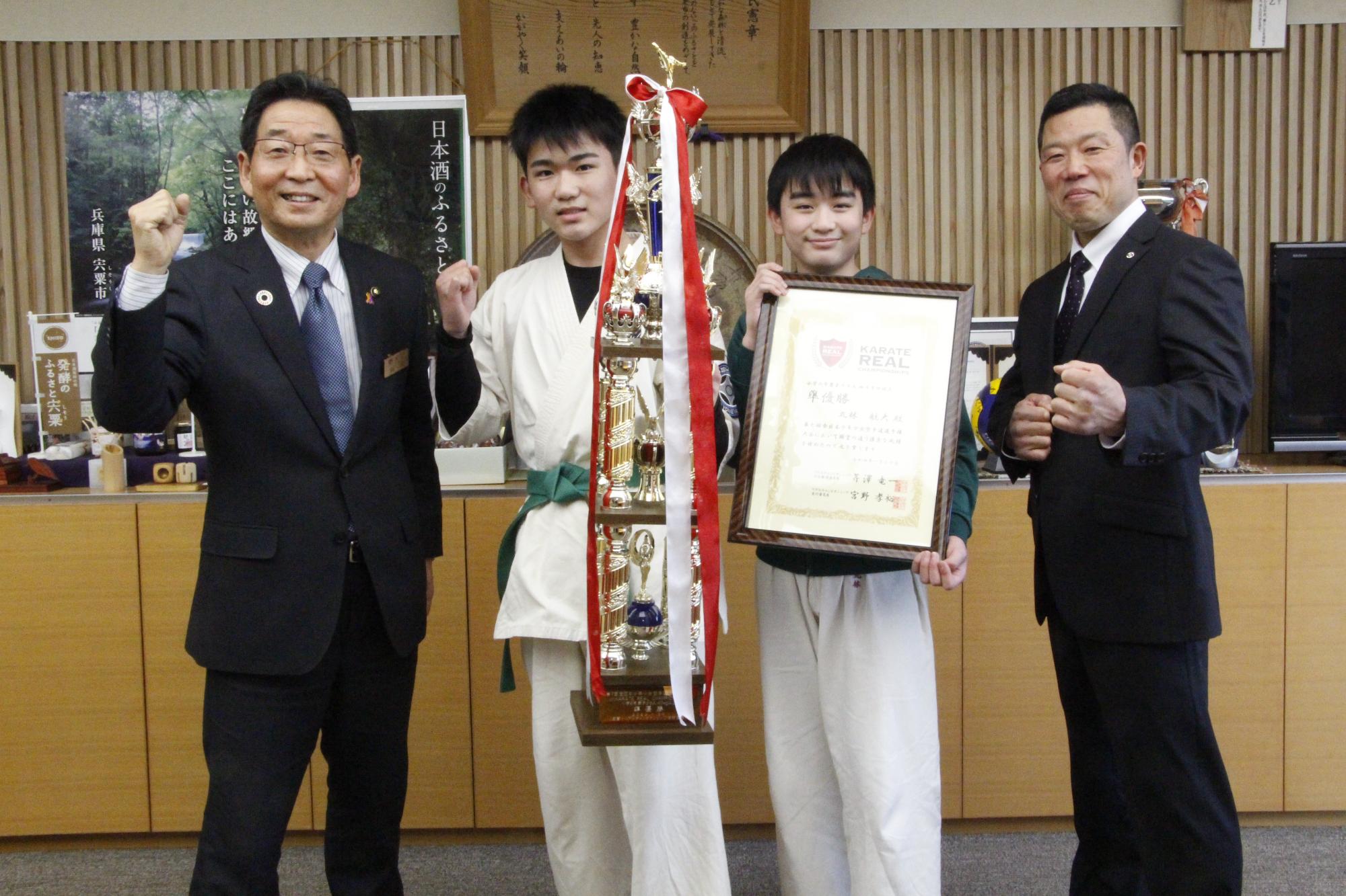 左から福元市長、丸林航大さんがトロフィーを手にガッツポーズをしている写真