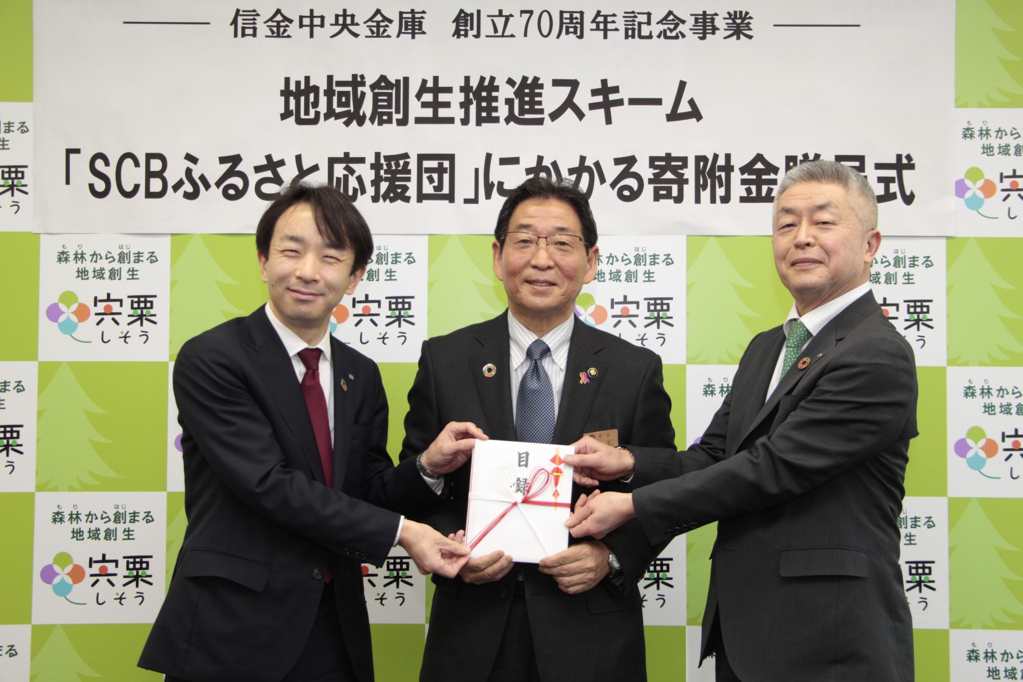 左は信金中金小平神戸支店長、中は福元市長、右は西信桑垣理事長が目録を手に並んでいる写真