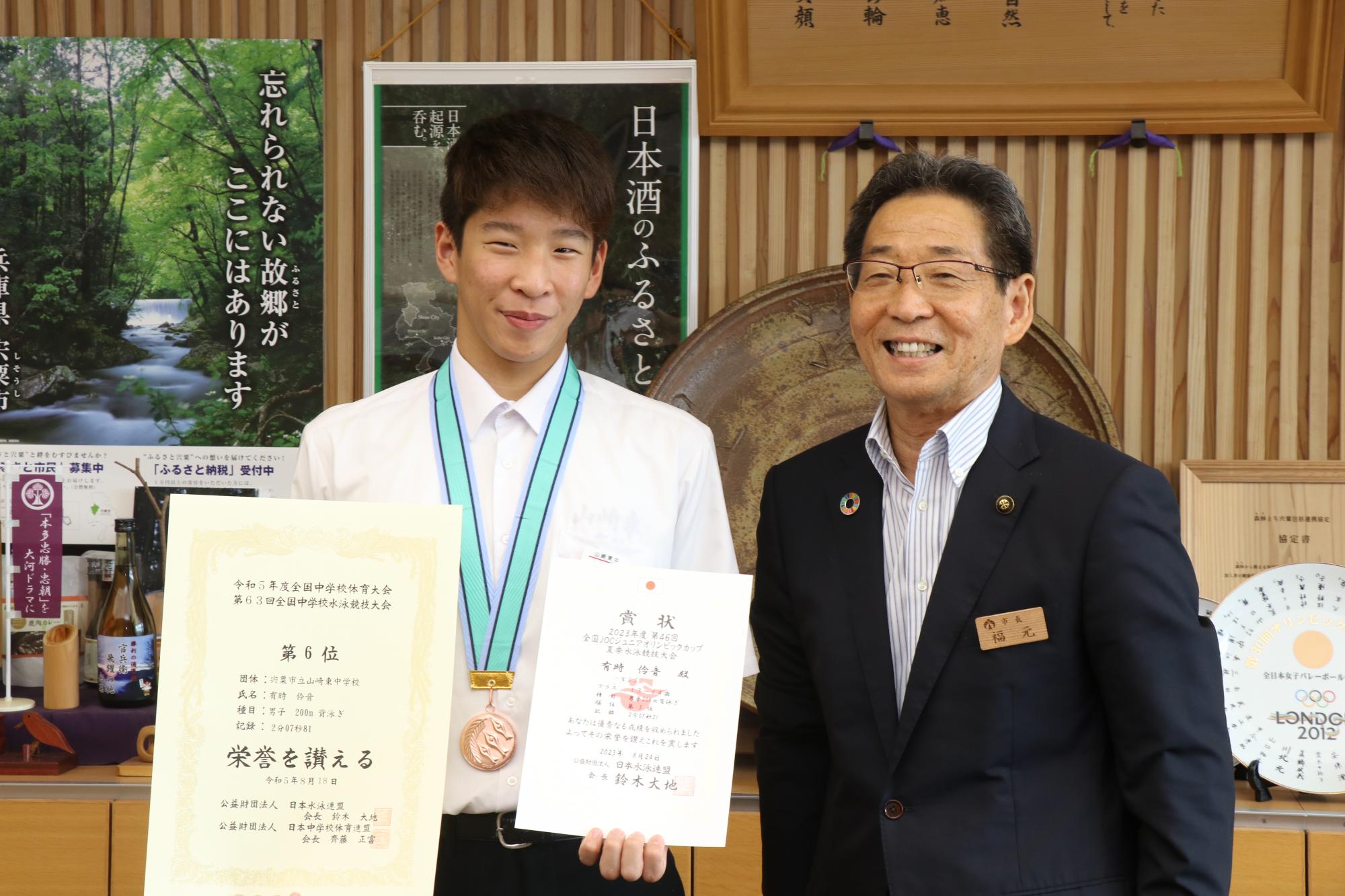 表彰状を手にした山崎東中学校水泳部の有時さんと福元市長が並んでいる写真
