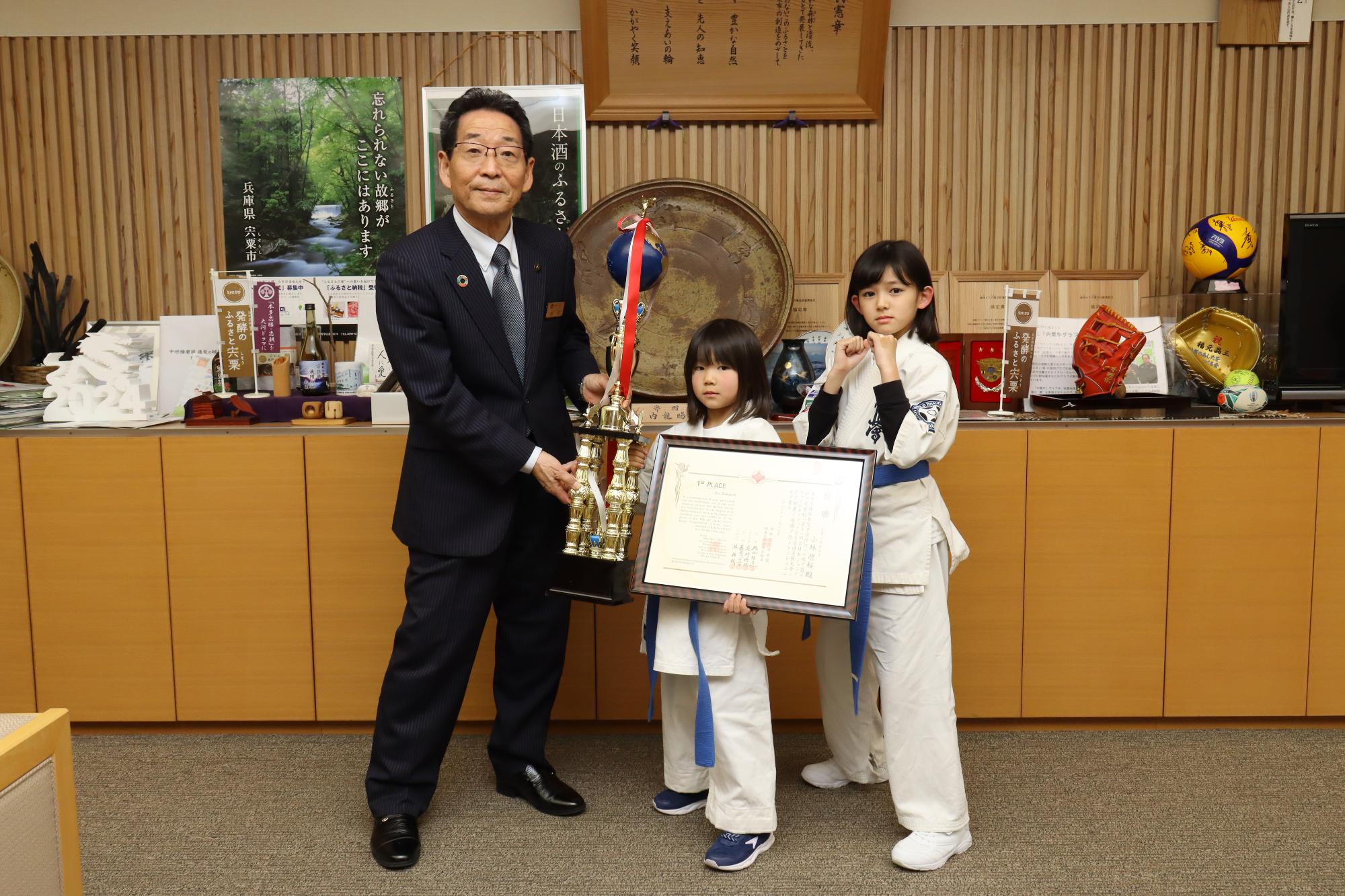 福元市長と空手全国大会優勝トロフィーと表彰状を手にした小林さんと坂井さんの記念撮影