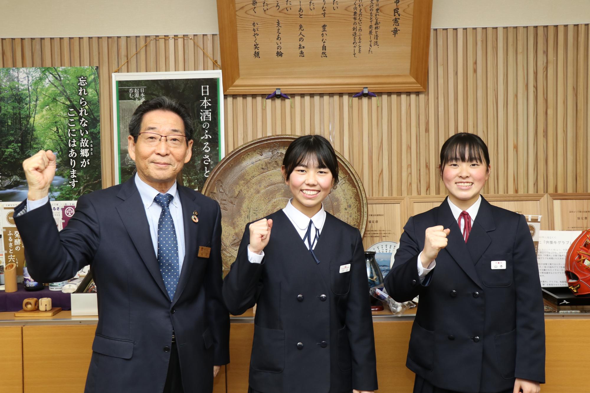 福元市長とスキー全国大会出場に向けてガッツポーズを決める一宮南中の川上さん、千種中の山本さん